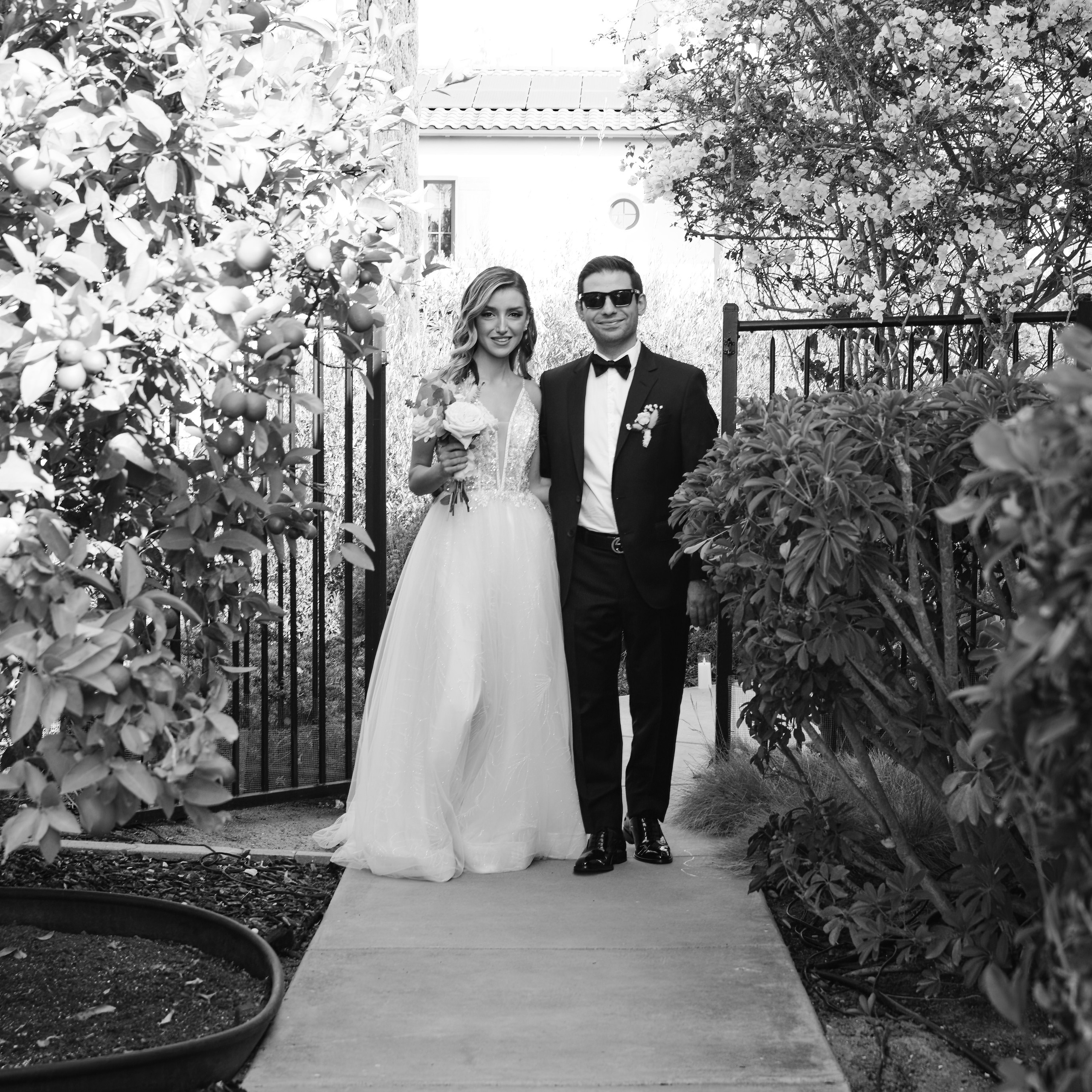 Bride and groom walking hand in hand along tree-lined path during wedding session
