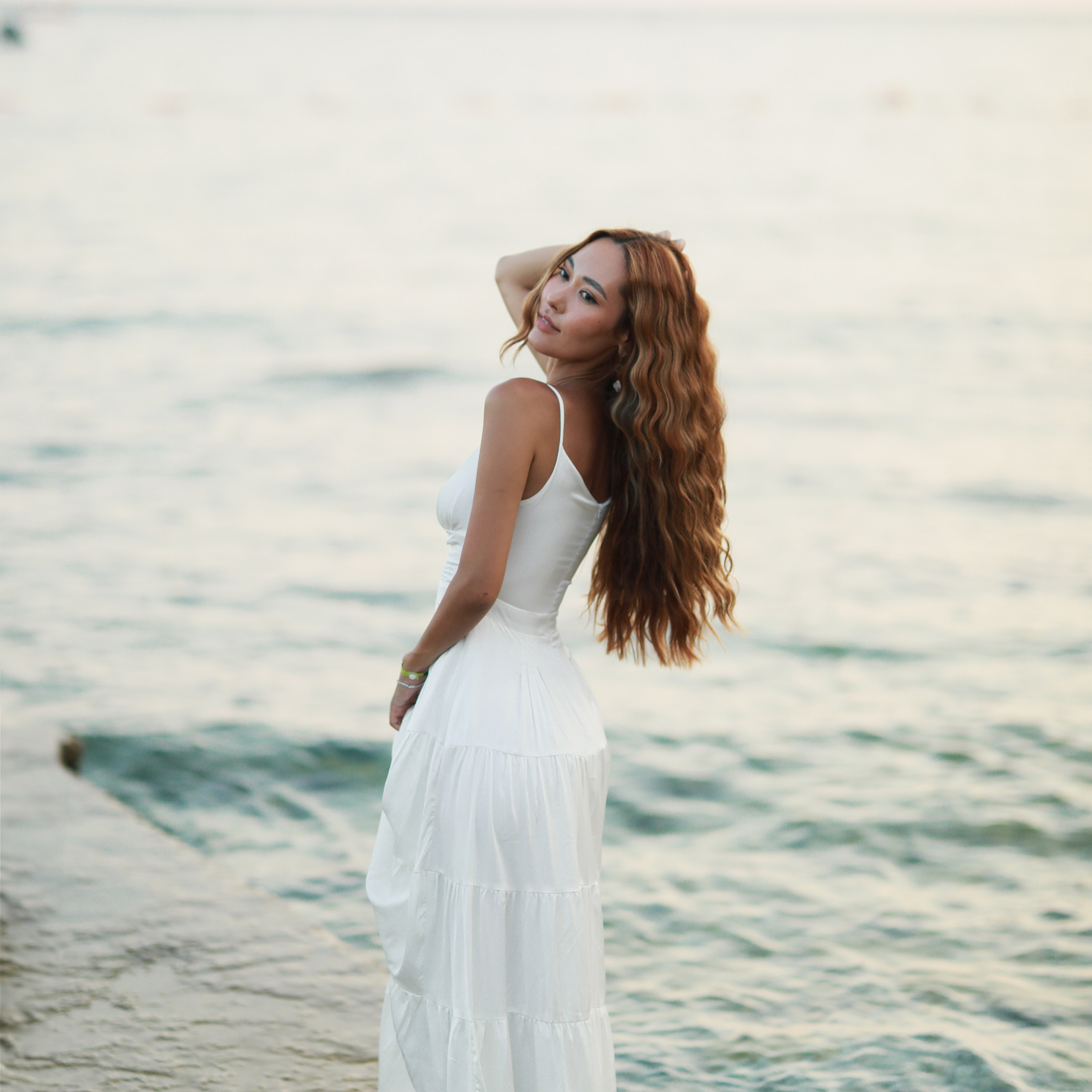 Bride standing by the sea in Croatia during a wedding photoshoot at sunset