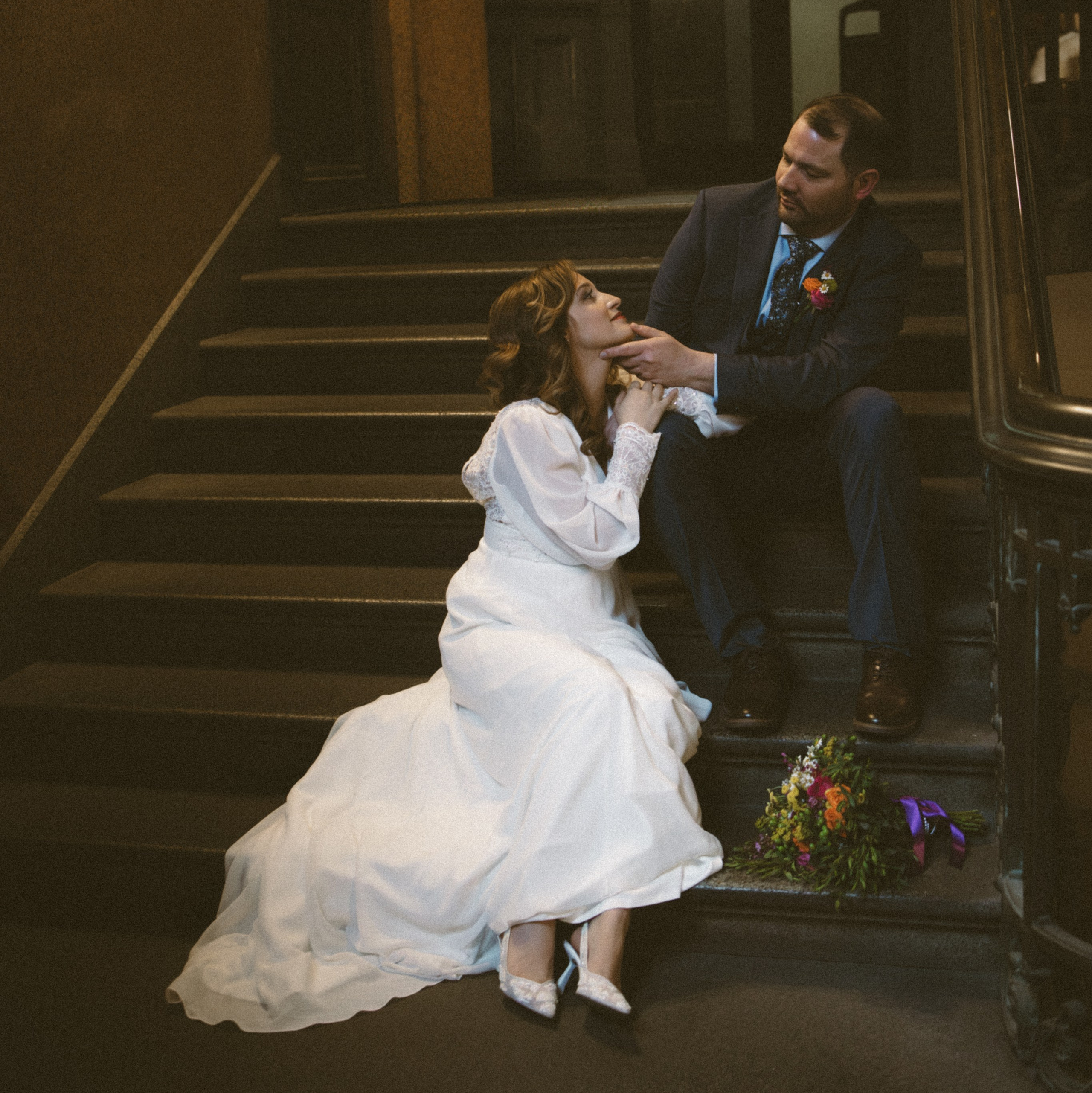 Bride and groom sitting on beautiful staircase at wedding venue for classic couple portraits"