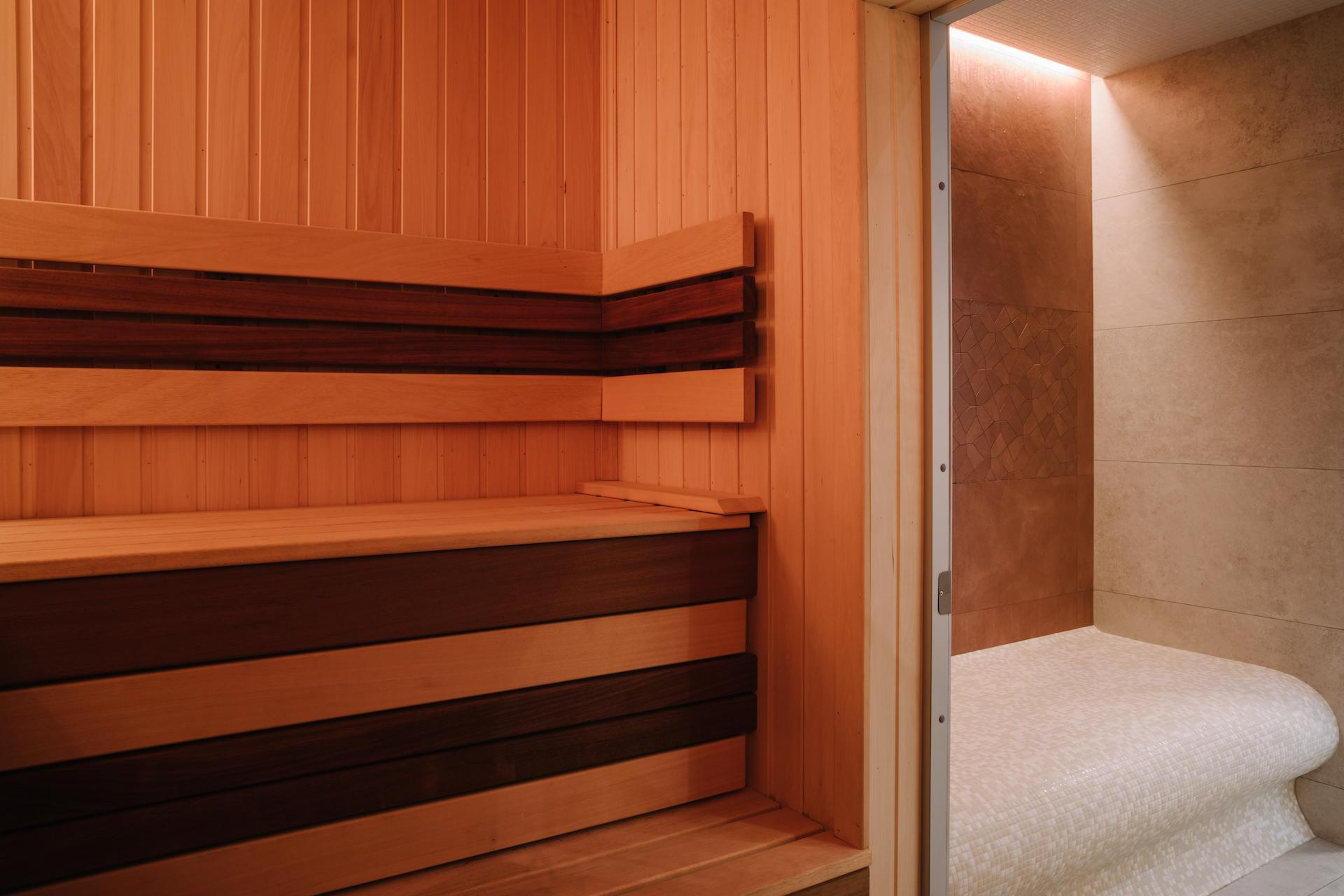 Интерьер сауны, с деревянными стенами, полками и печкой для нагрева камней.