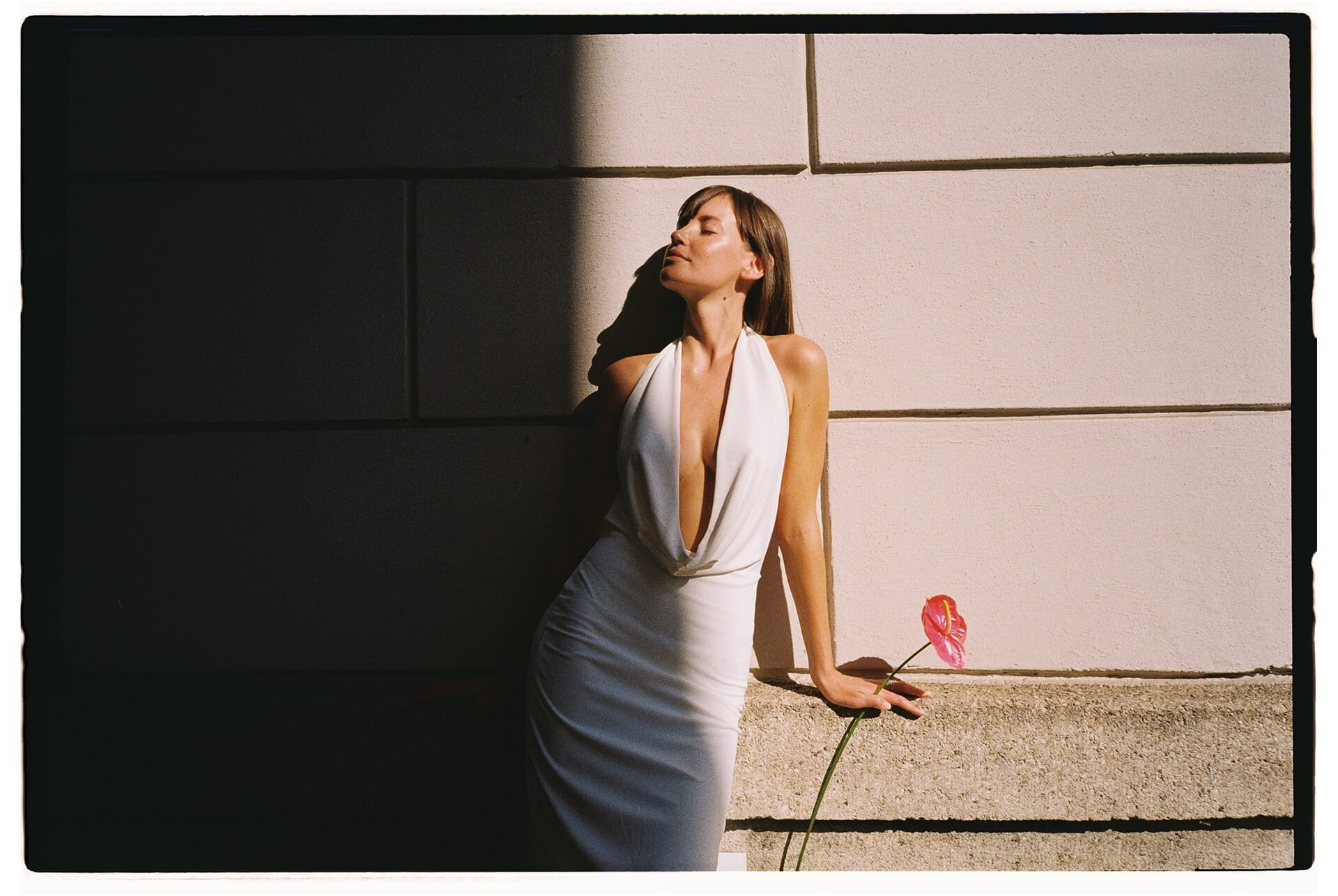Editorial bridal portrait: bride in a white gown against a dark wall