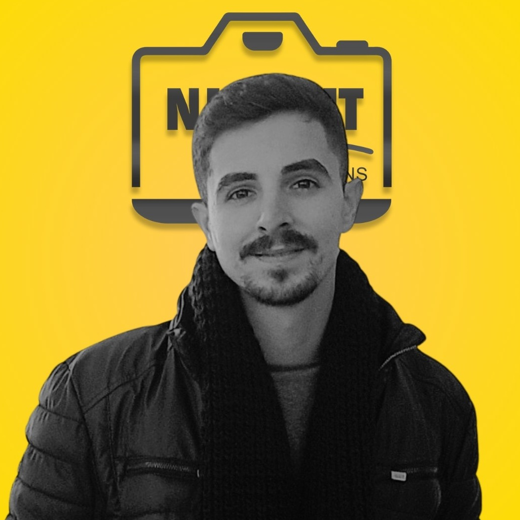 Portret profesional al unui bărbat pe fundal galben cu logo, expresie zâmbitoare