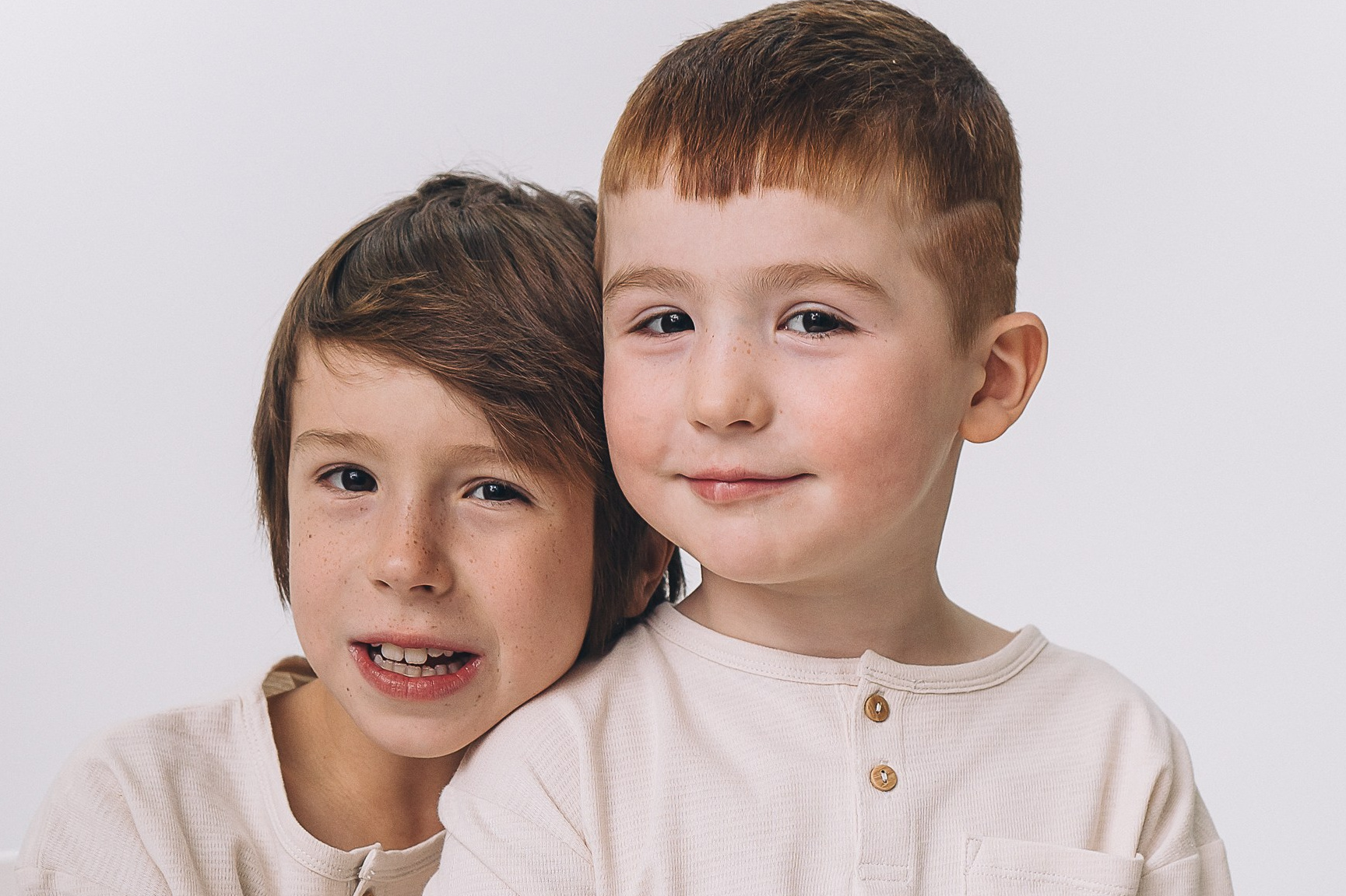 Two brothers sitting closely to each other looking content, smiling