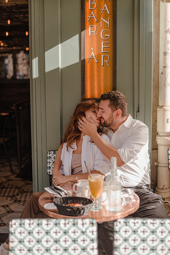 A couple kissing at Parisian Café on Place Dauphine during a photoshoot
