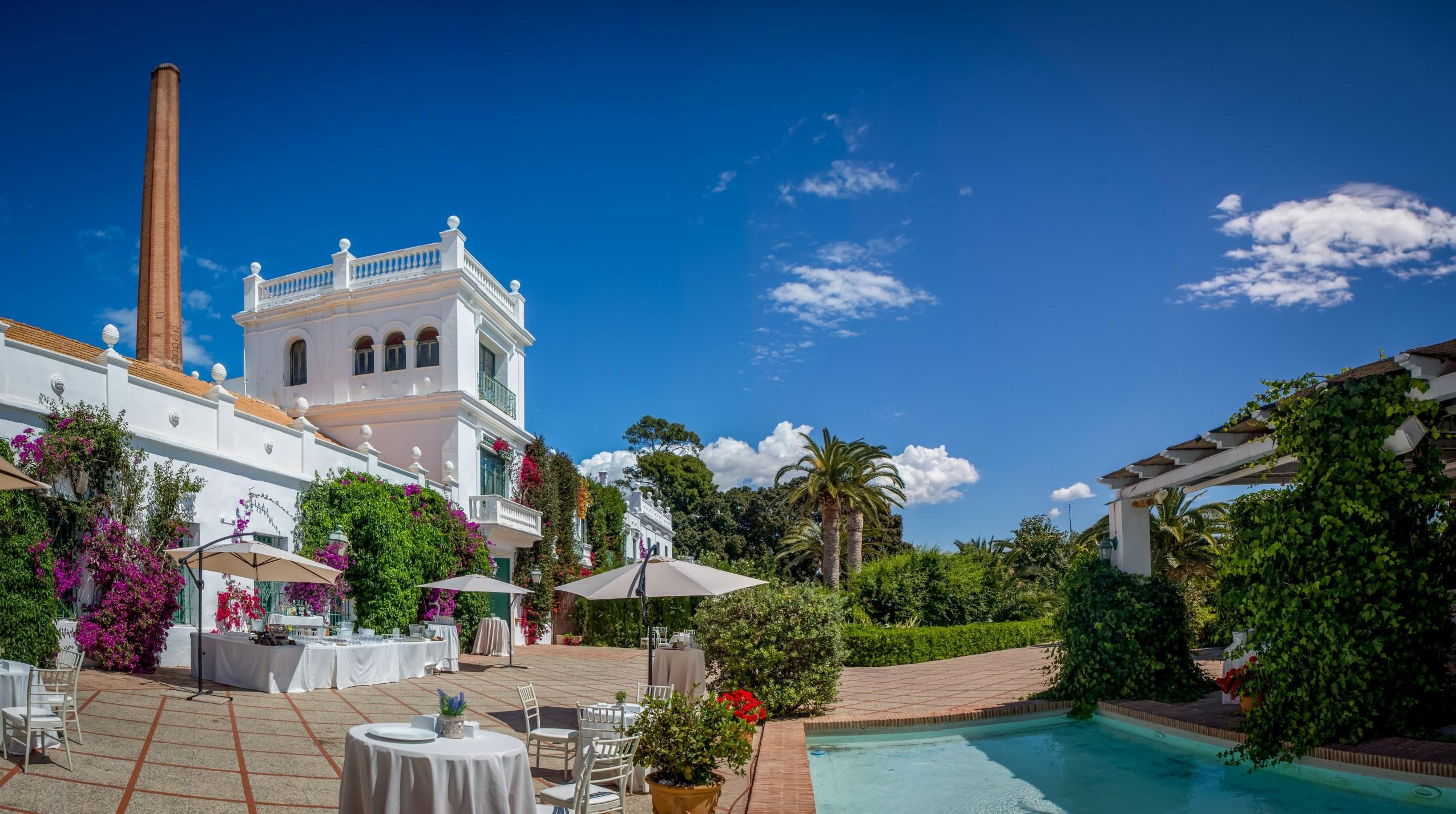 Campo Aníbal wedding venue with a white façade, flowering vines and reception tables beside a courtyard pool.