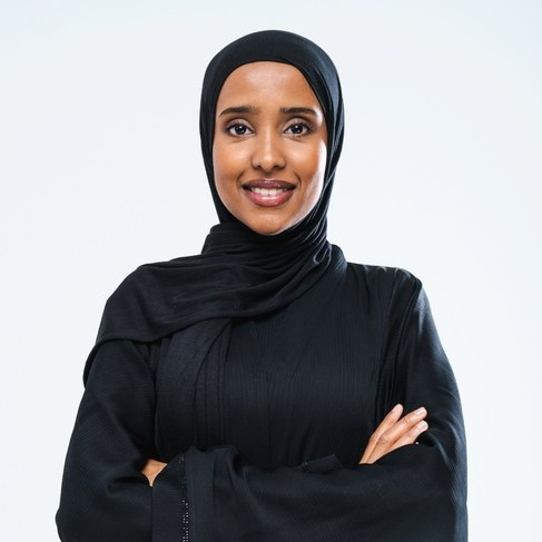Portrait of a woman wearing traditional black attire, standing with a positive expression