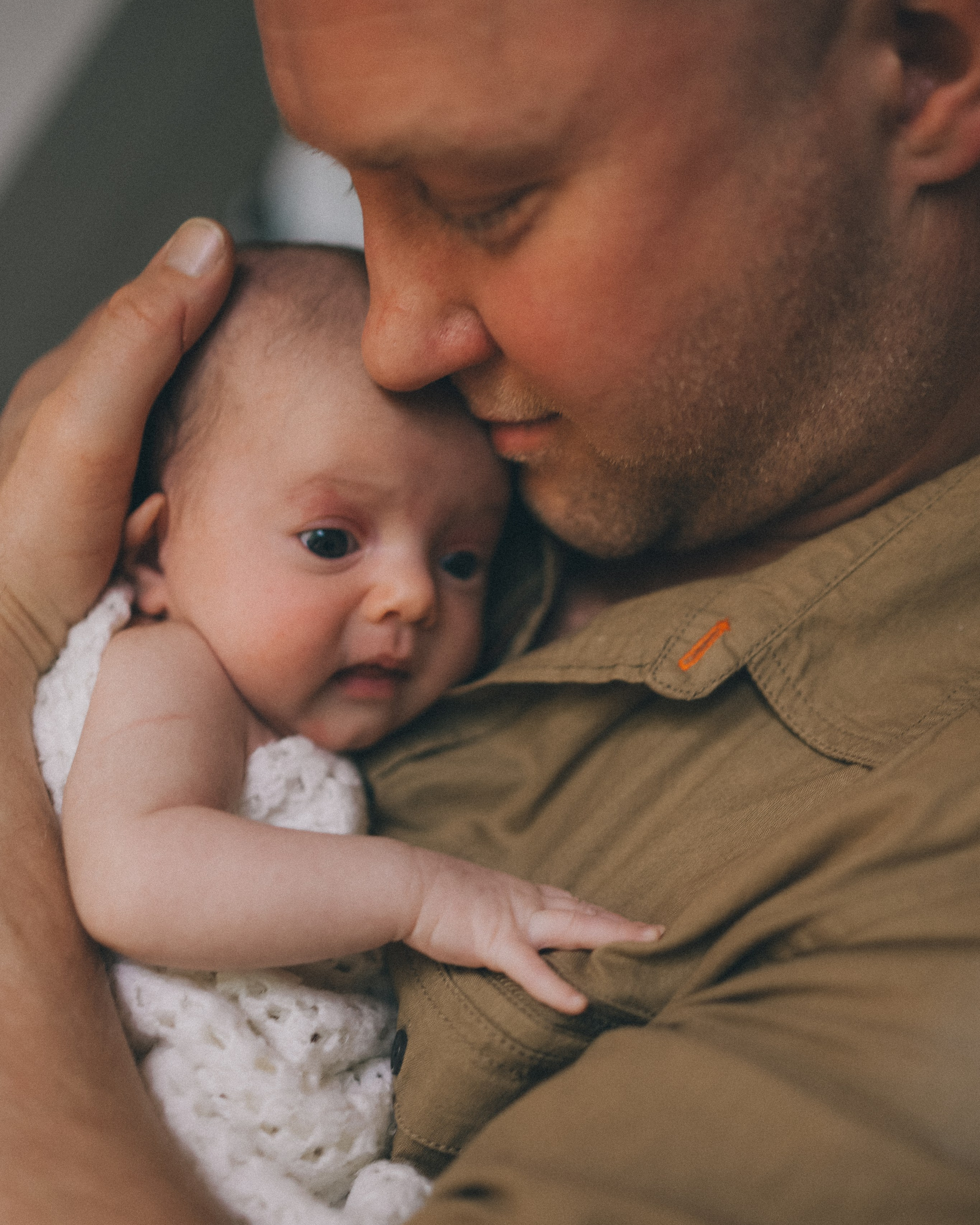 Leamington Spa newborn photo session in comfort of your home. Dad hugging his newborn daughter. Candid newborn photography. 