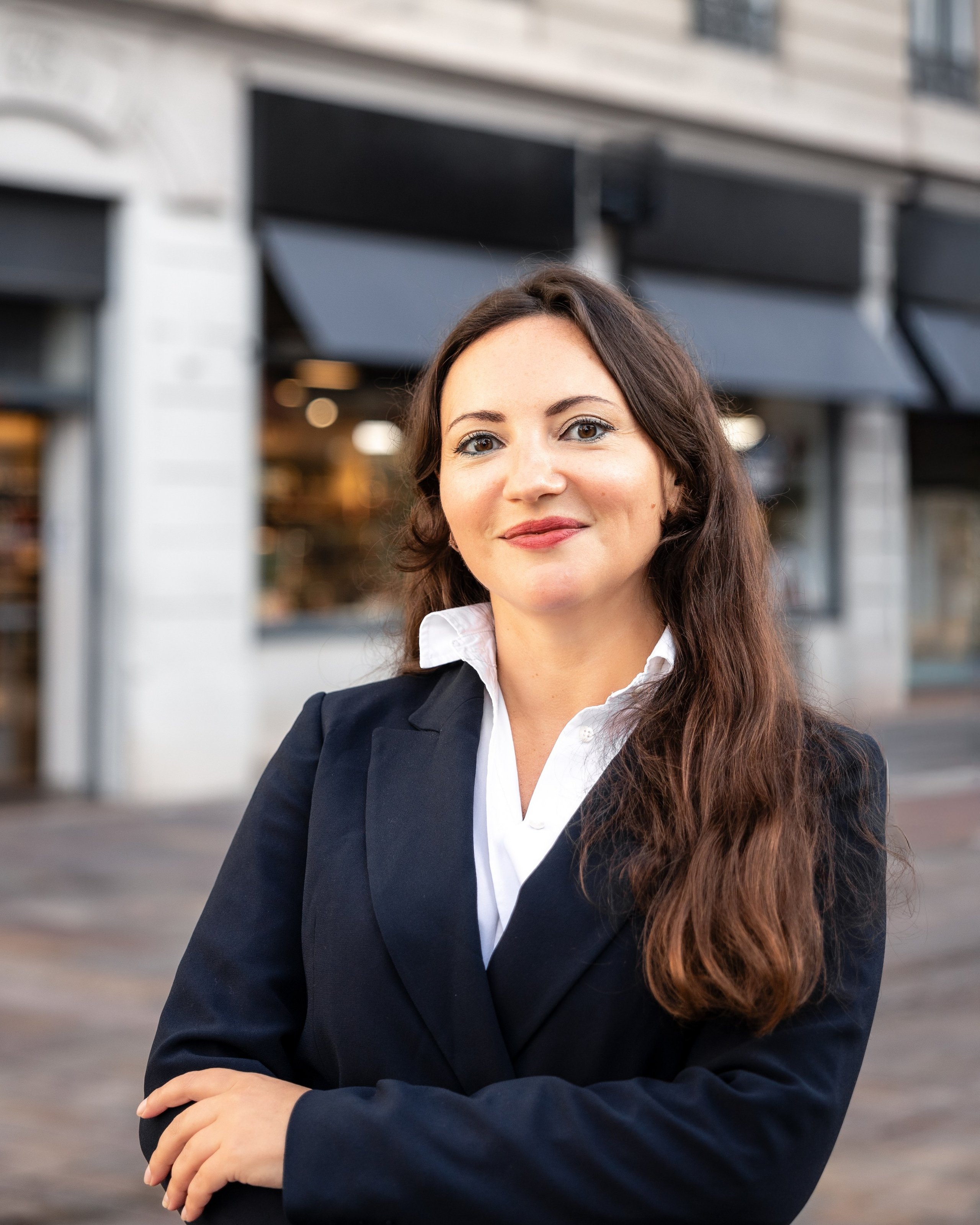 professional portrait of a woman in a dark blazer standing outdoors in an urban setting