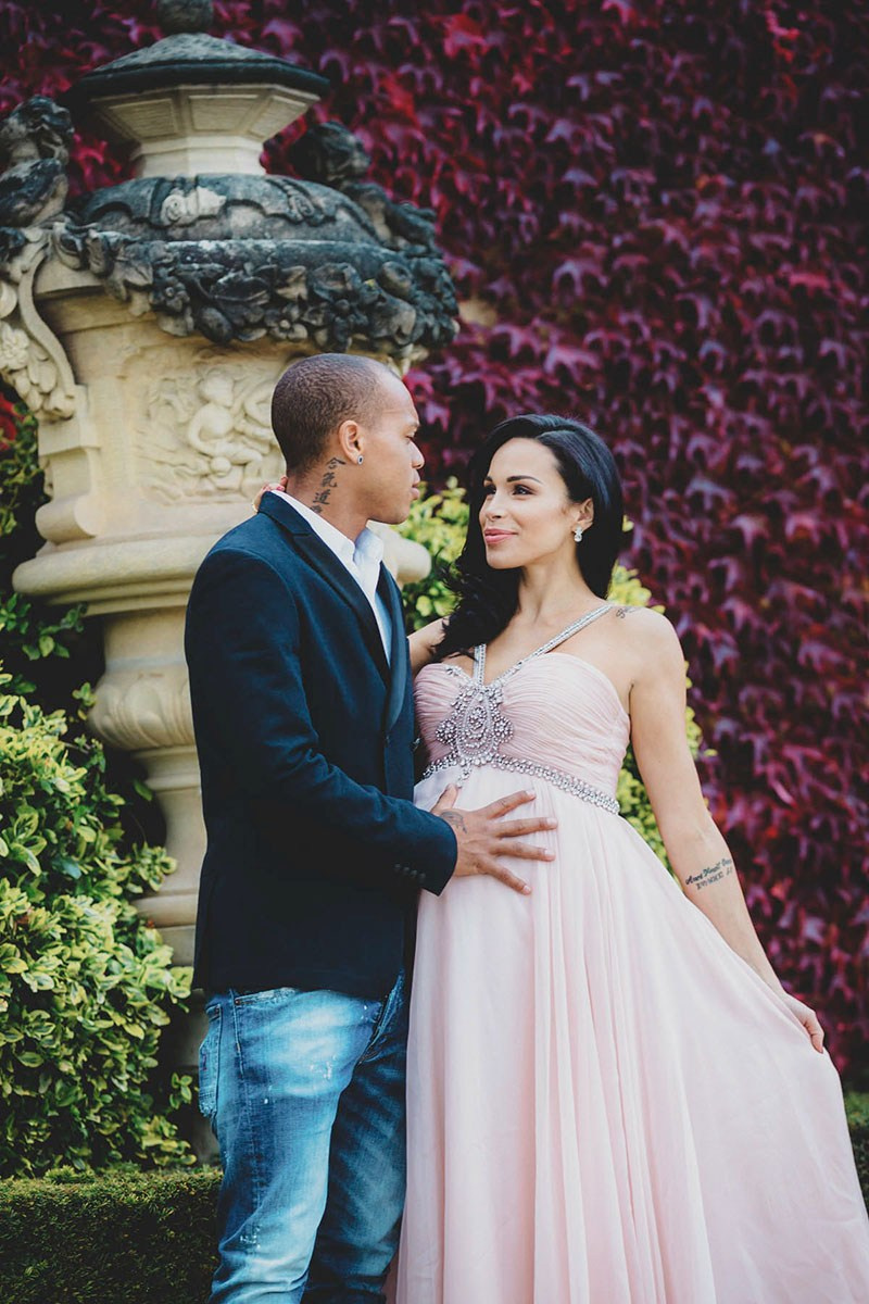 An expectant couple face to face beside a stone urn in front of red ivy at Vrtba Garden