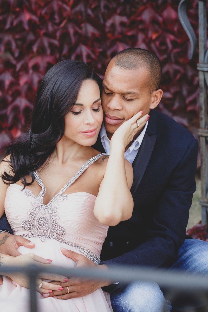 Close portrait of an expectant couple with their eyes closed, her hand on his cheek