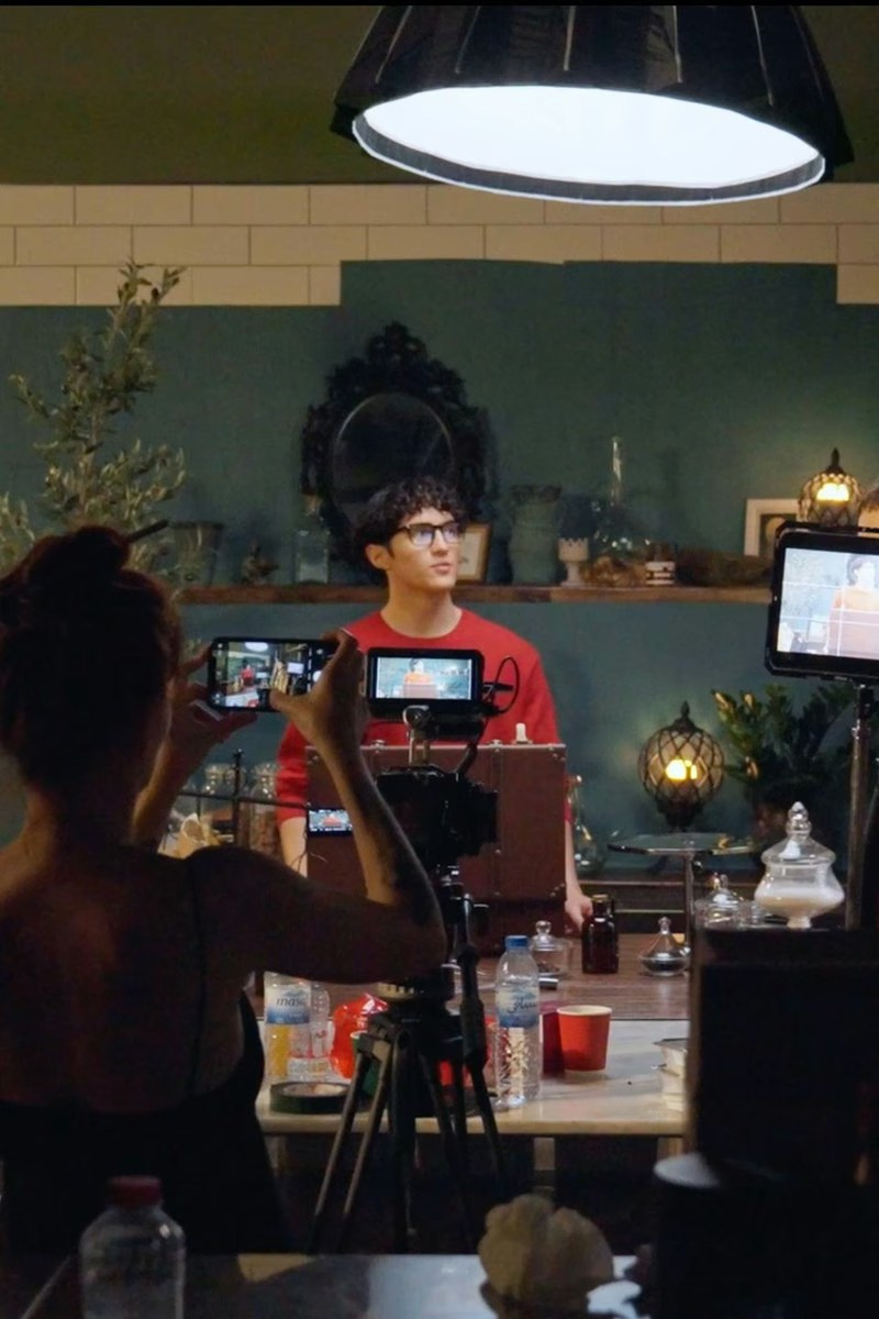 Team working on a fashion photoshoot, with a stylist adjusting the model's outfit while others observe