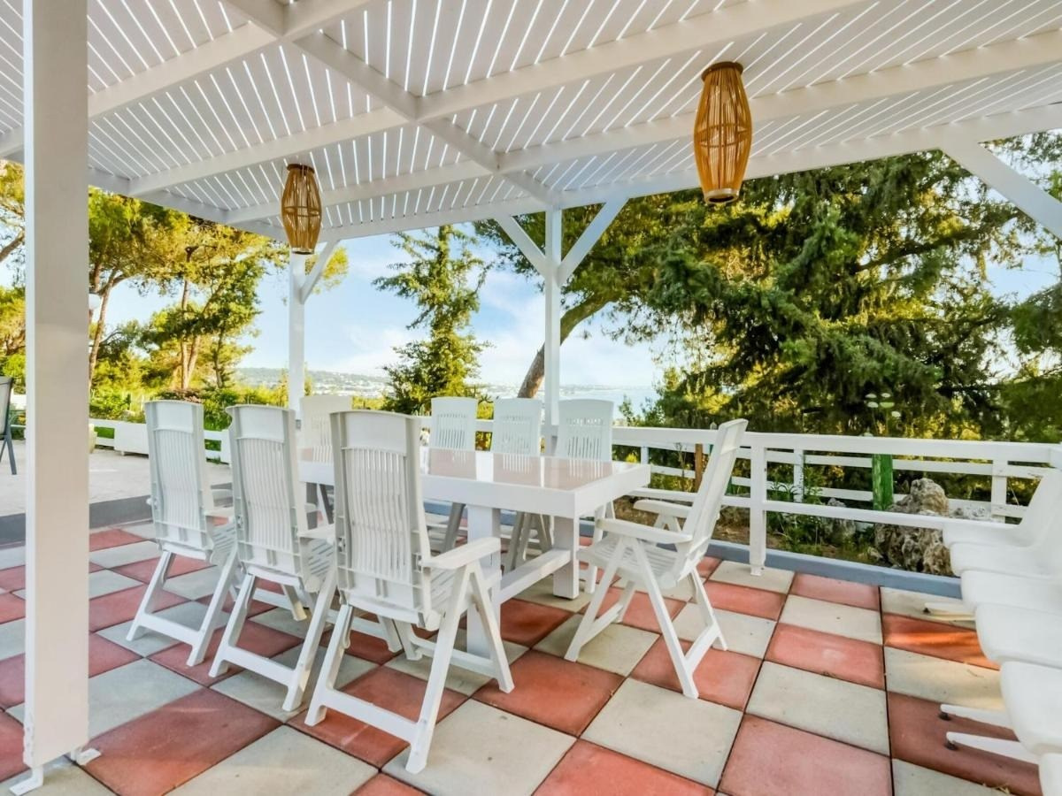 Luxusvilla Rhodos mieten: Terrasse der Villa Louis in Koskinou mit großem Esstisch, Pergola und Meerblick. Exklusive Ferienvilla auf Rhodos für Gruppen und Familien, Außenbereich mit Gartenmöbeln und mediterranem Flair.