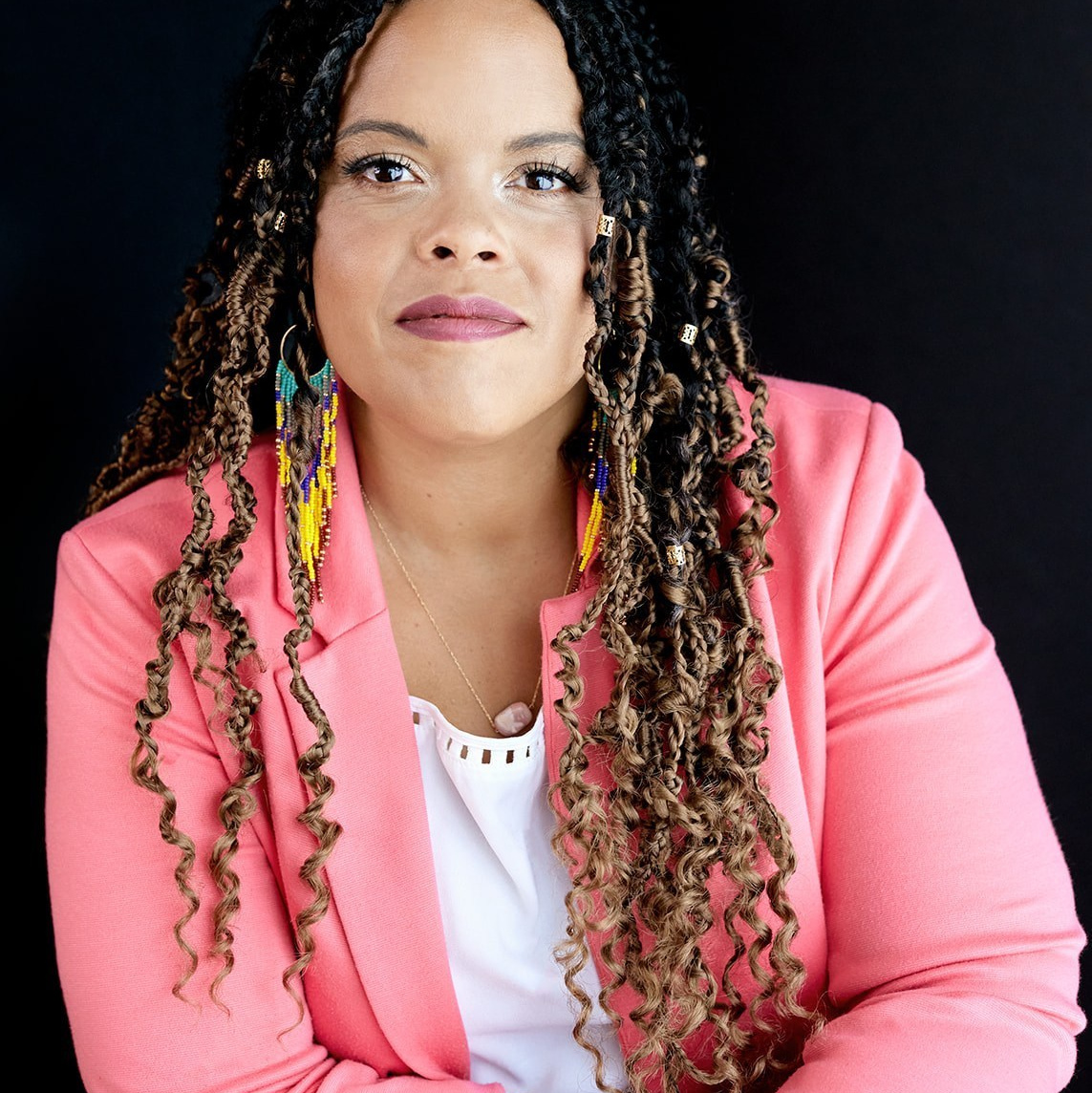 HEADSHOT OF ABORIGINAL WOMAN IN PINK BLAZER WITH BRAIDS IN HAIR