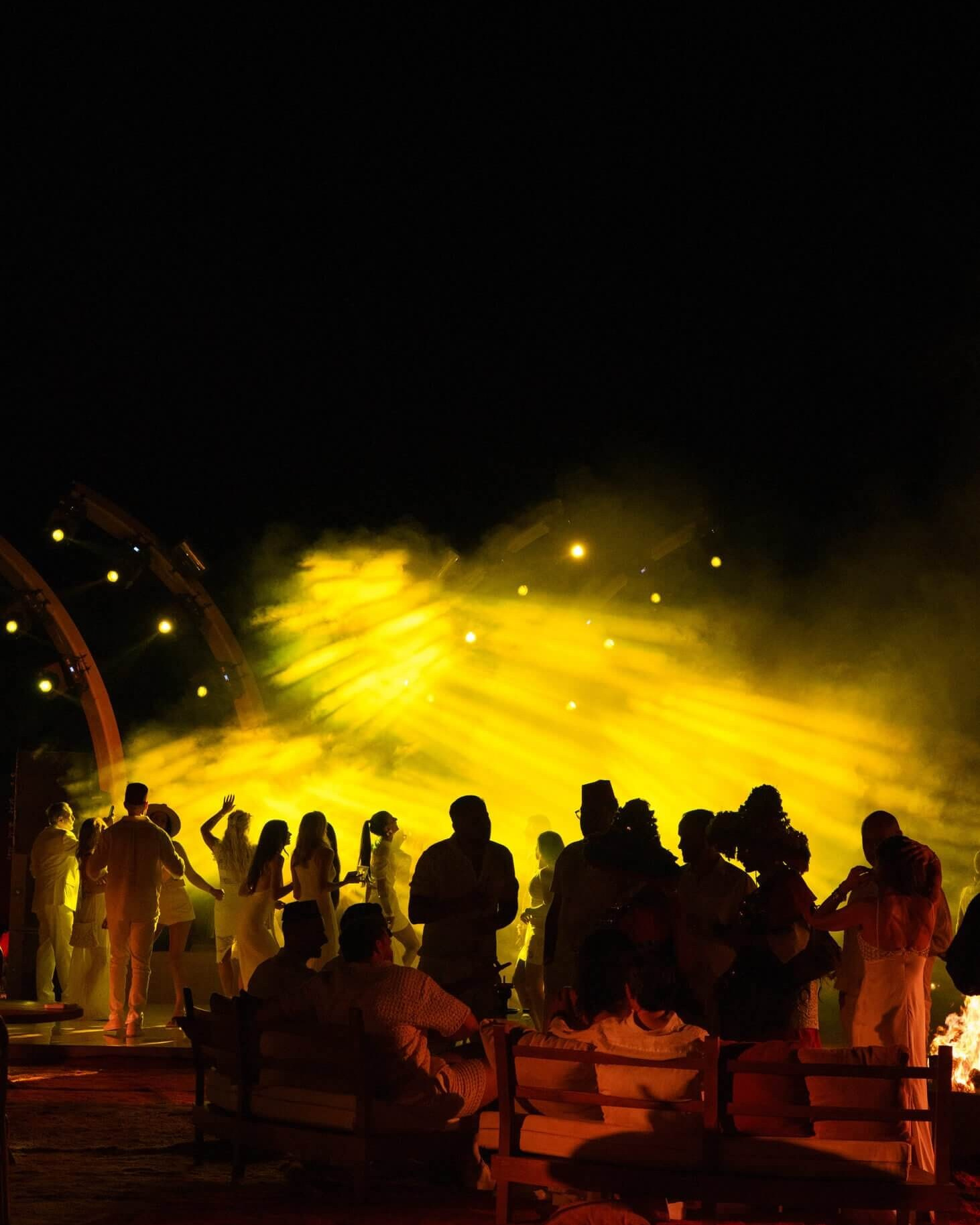 Guests gathered in dramatic yellow light during an evening wedding celebration in Marrakech