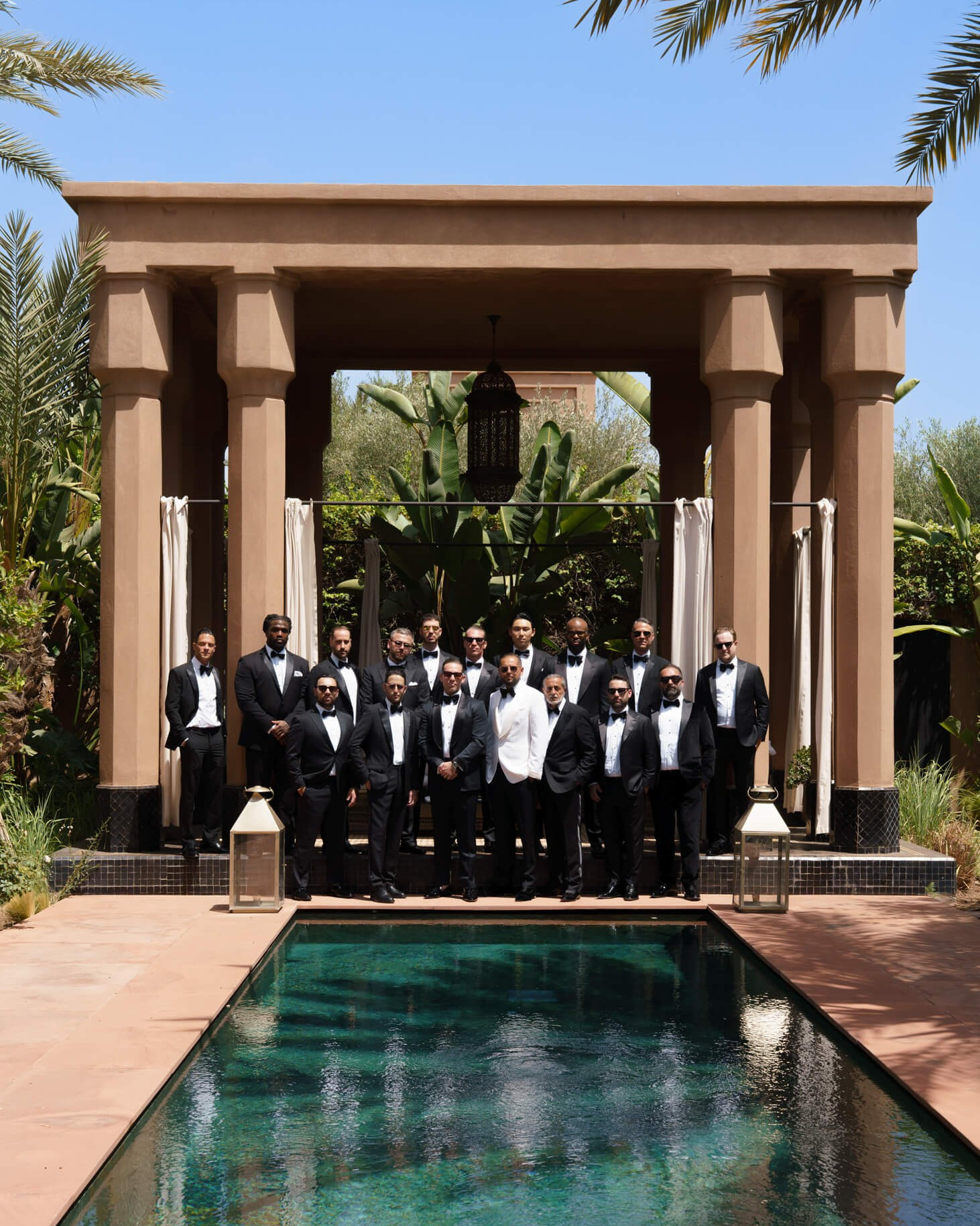 Wedding guests dressed in black posing by a pool at a luxury wedding venue in Marrakech