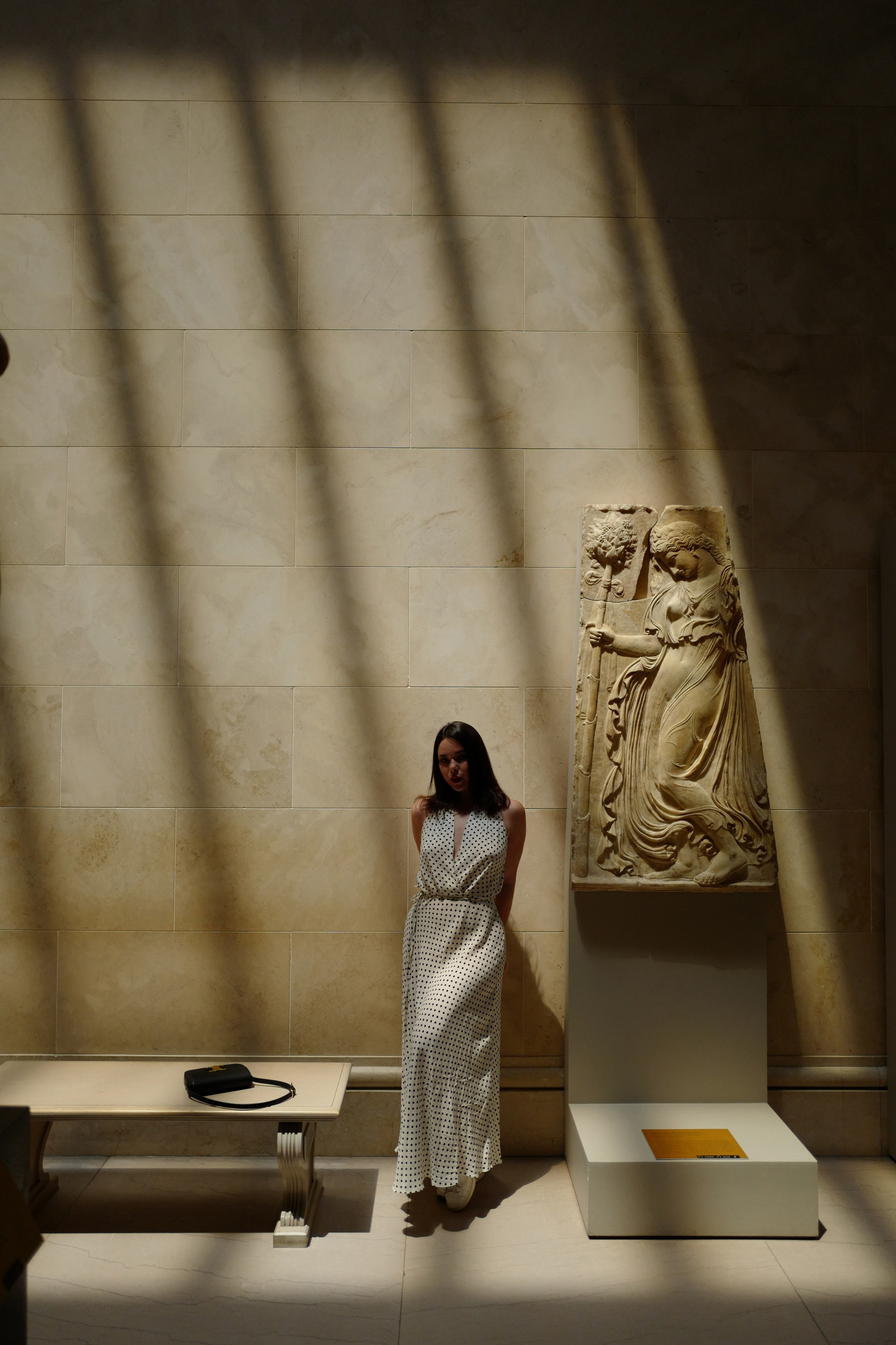 a woman standing in a museum looking at a sculpture