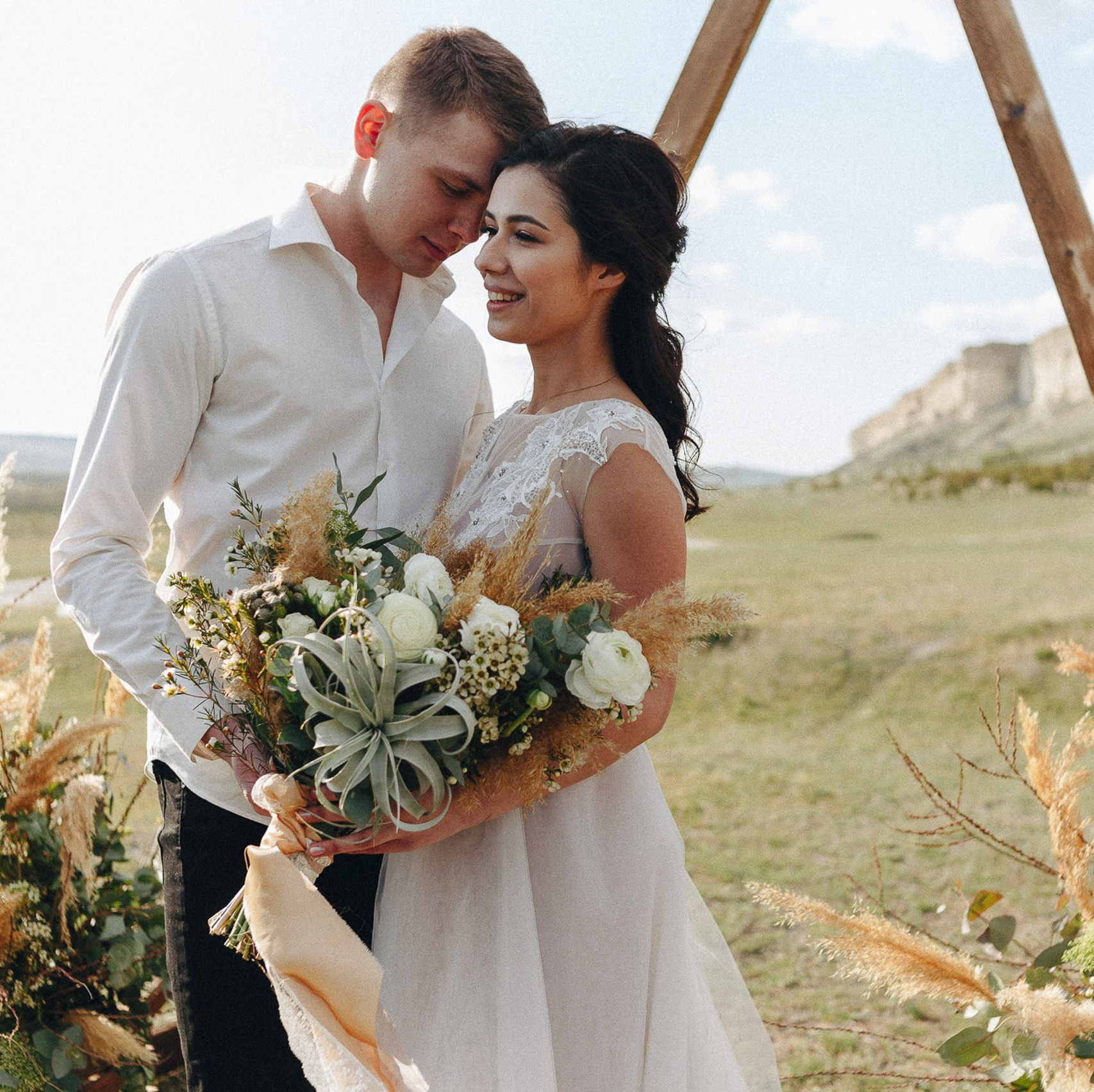 Bride and groom kissing outdoors with floral arch