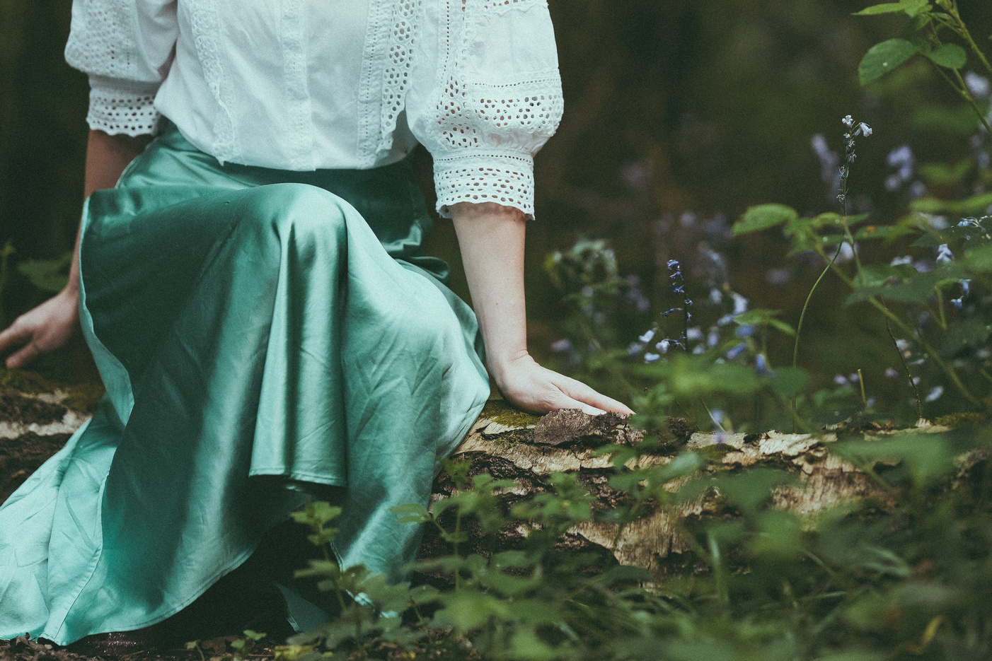 Woman sitting among greenery in Clowes Wood Warwickshire, atmospheric forest portrait in natural light