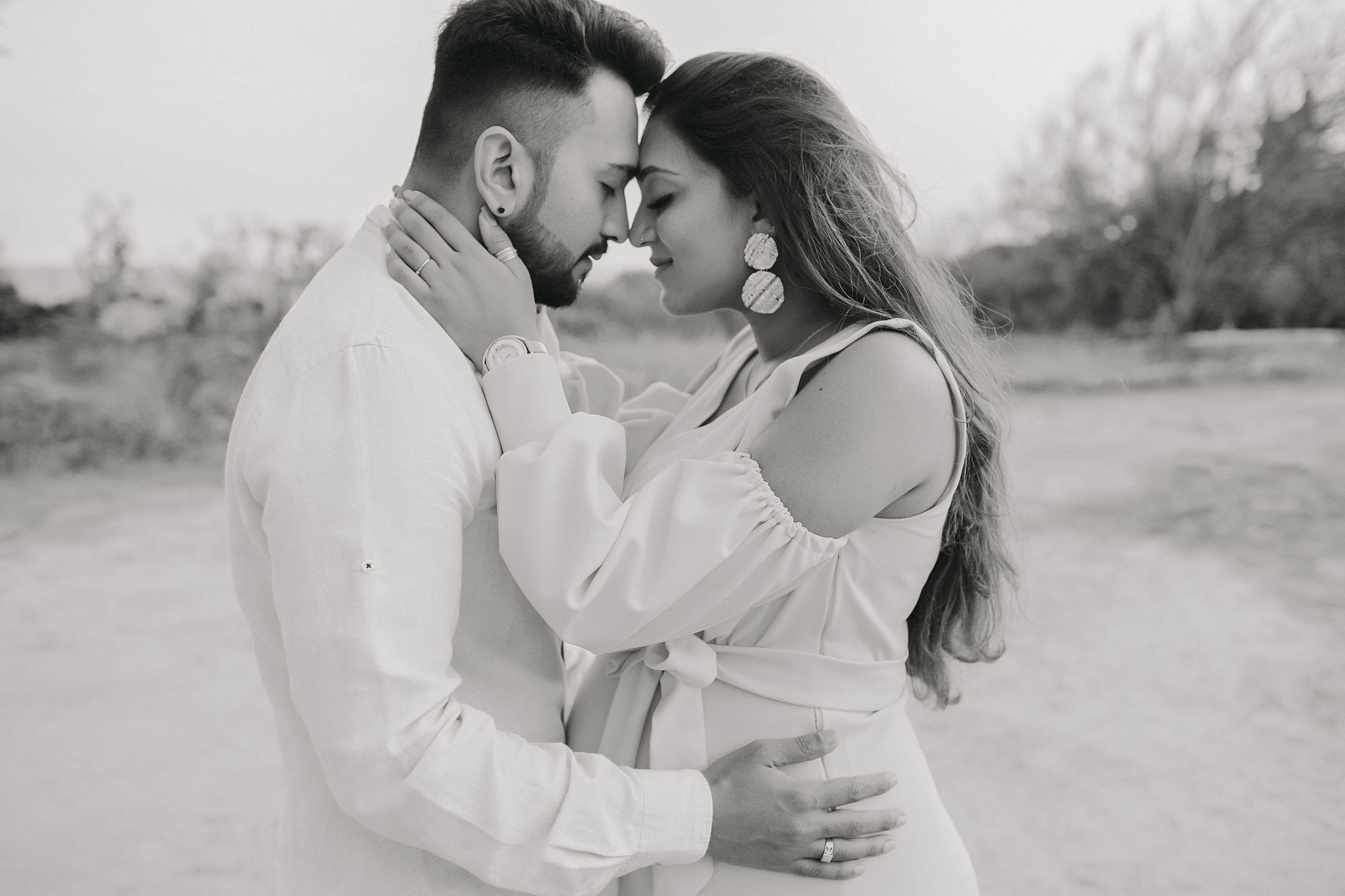 Tender kiss during vintage-inspired maternity photoshoot, soft B&W tones, Mombasa garden, Kenya.