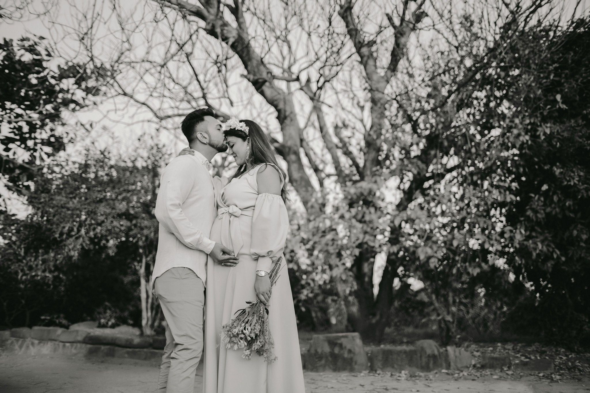 Couple moment during pregnancy shoot, with vintage tones and Kenyan garden backdrop.