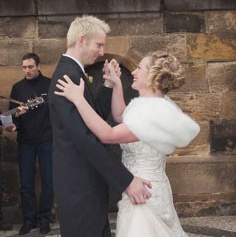 Smiling blonde-haired Swiss bride smiles lovingly towards her Italian groom as he looks towards the camera at a garden in Prague. 