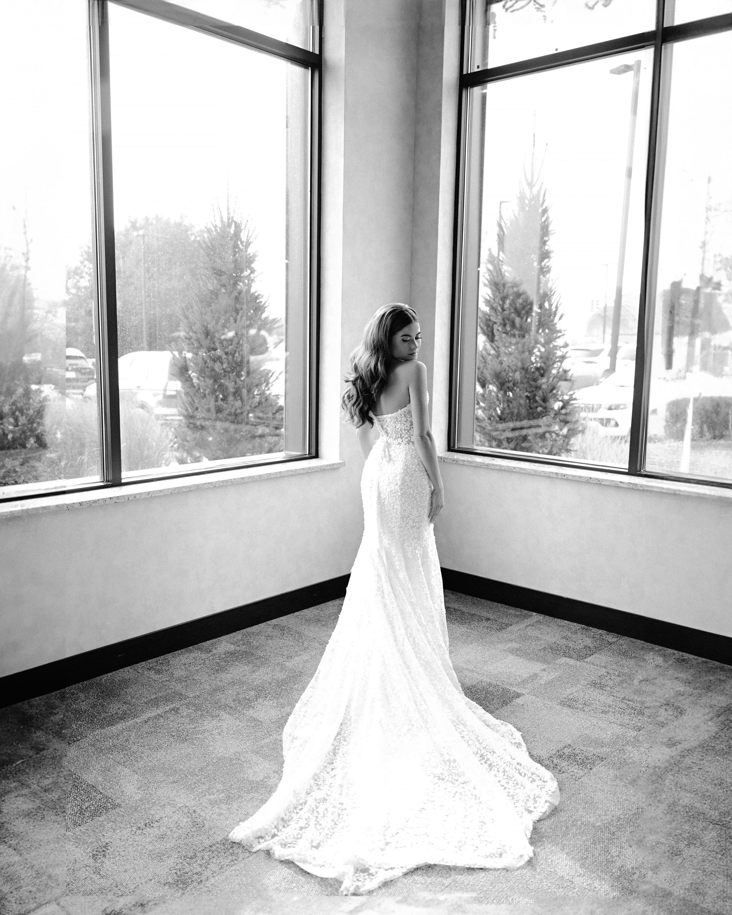 a bride in a white dress standing in front of a window