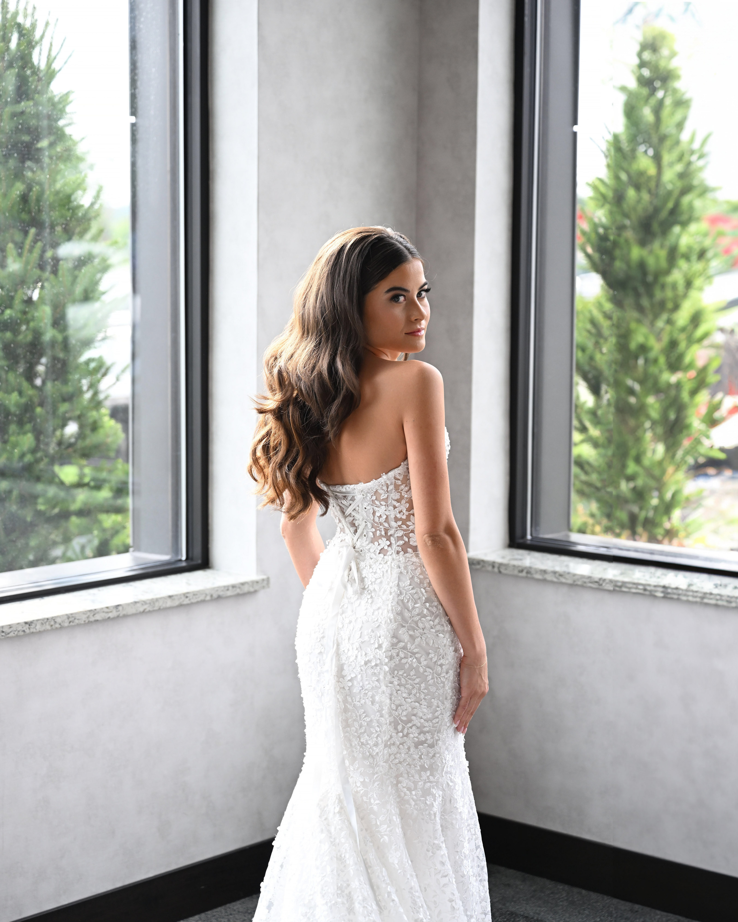 a woman in a wedding dress looking out the window