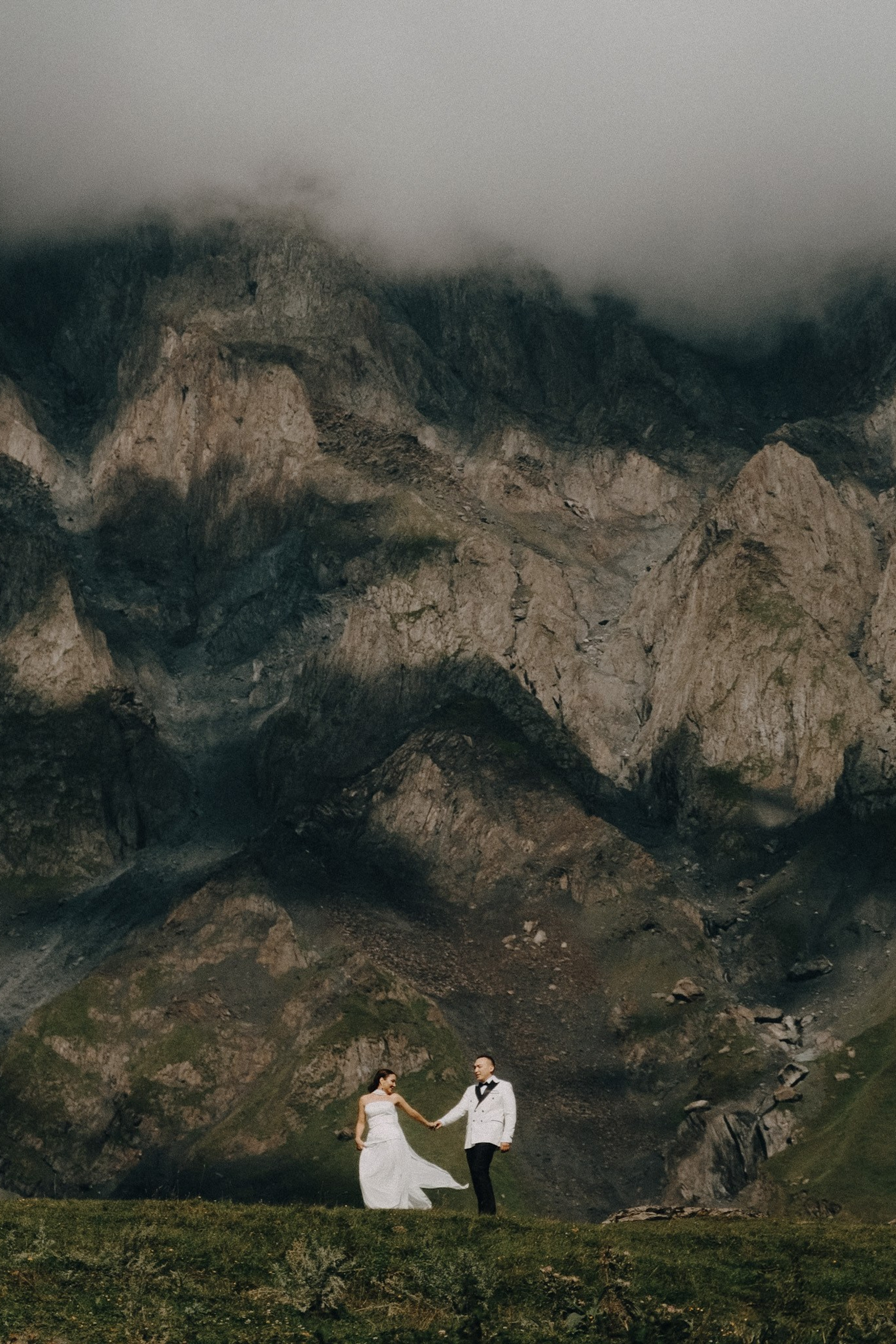 Bride and groom walking through summer meadows in Kazbegi