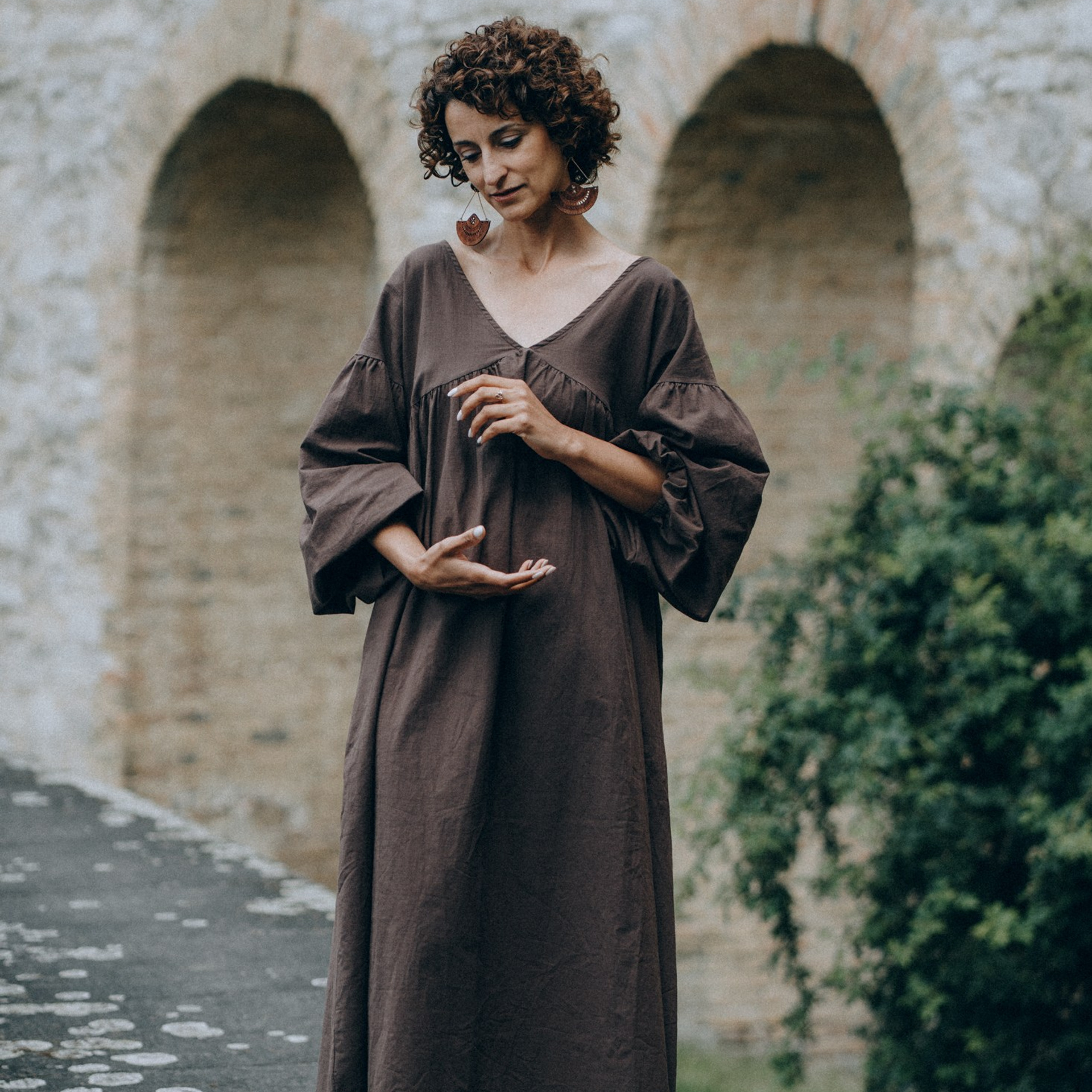 Natürliche Portraitfotografie – Frau in langem Kleid vor Steinbögen