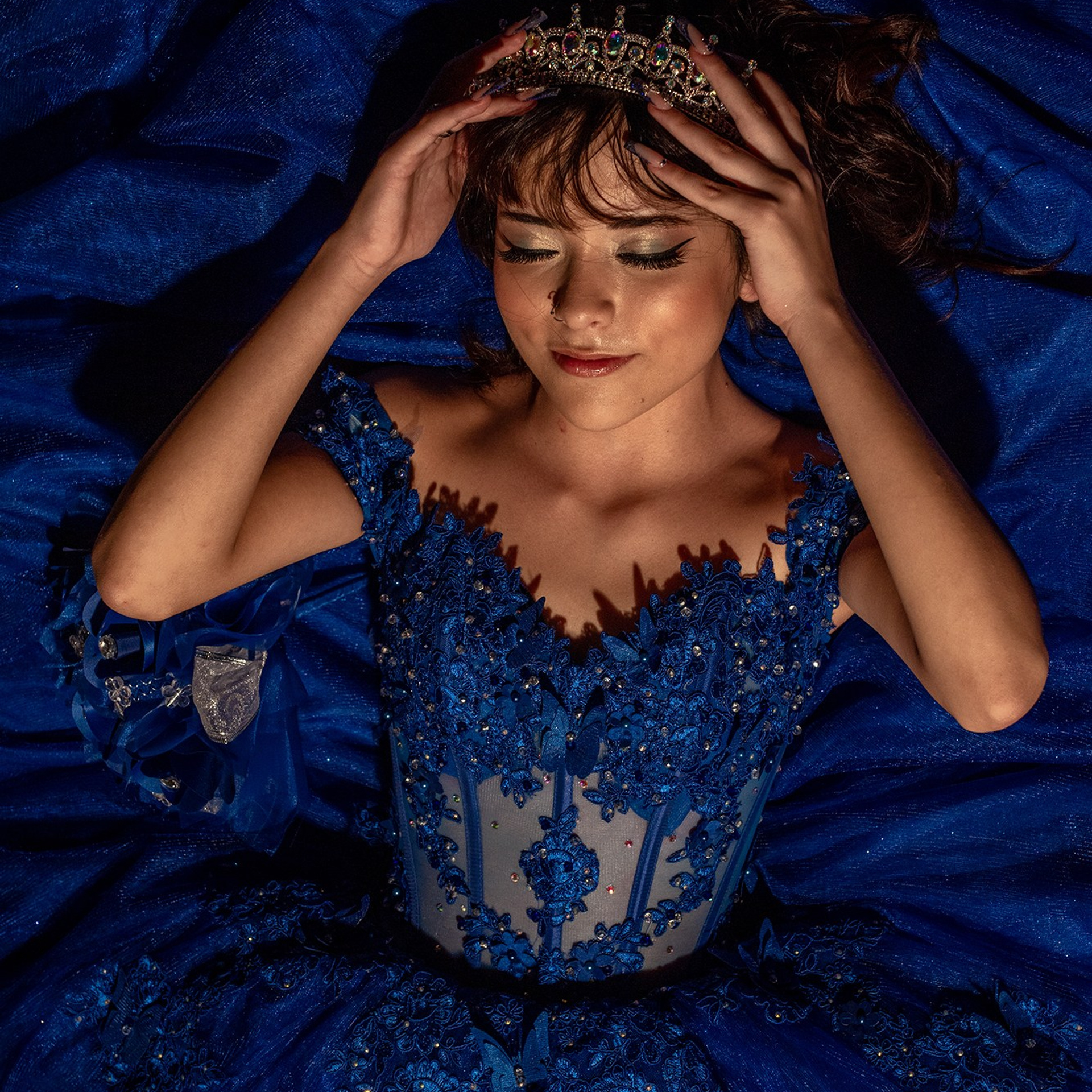 Quinceañera photography Los Cabos – Michelle in blue quince dress adjusting her crown, elegant sweet fifteen beach portraits at sunset, Cabo San Lucas XV años destination session.