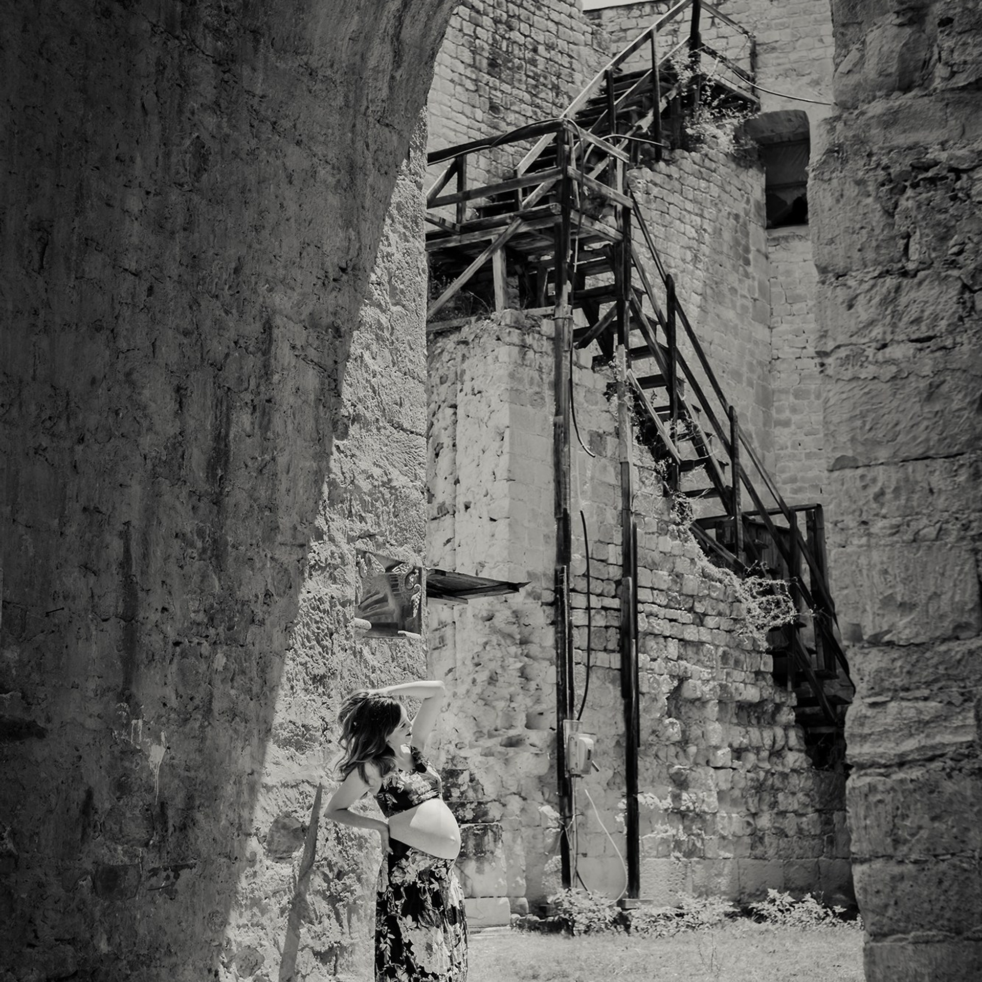 Elegant maternity photoshoot – pregnant woman posing in a rustic hacienda with stone arches, celebrating love, hope, and the journey of new life