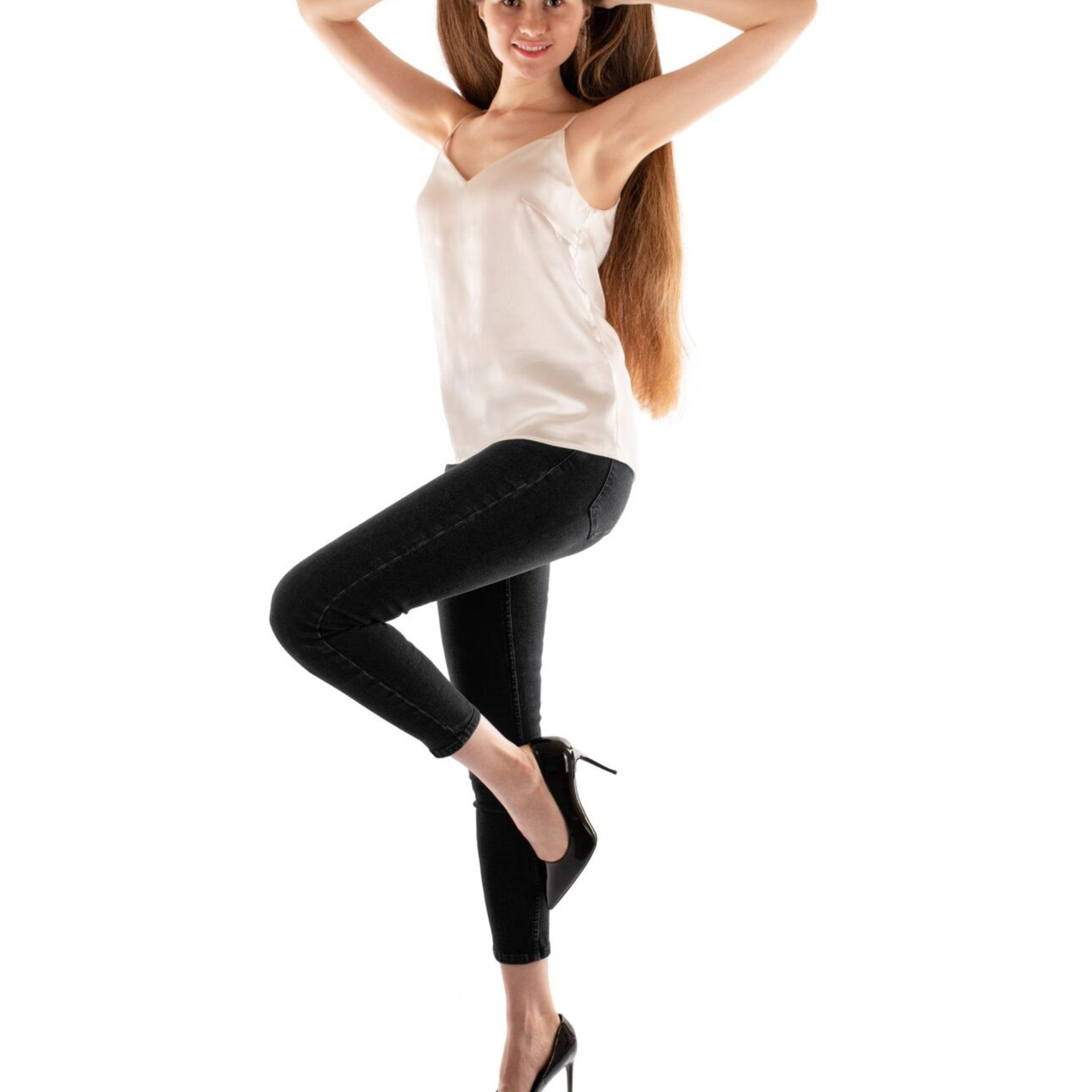 Professional beauty and fashion portrait featuring a young woman with long healthy hair posing in a studio on a white background. High-end photography with natural beauty retouching, clean styling, and detailed hair enhancement for haircare, beauty, and fashion brands.