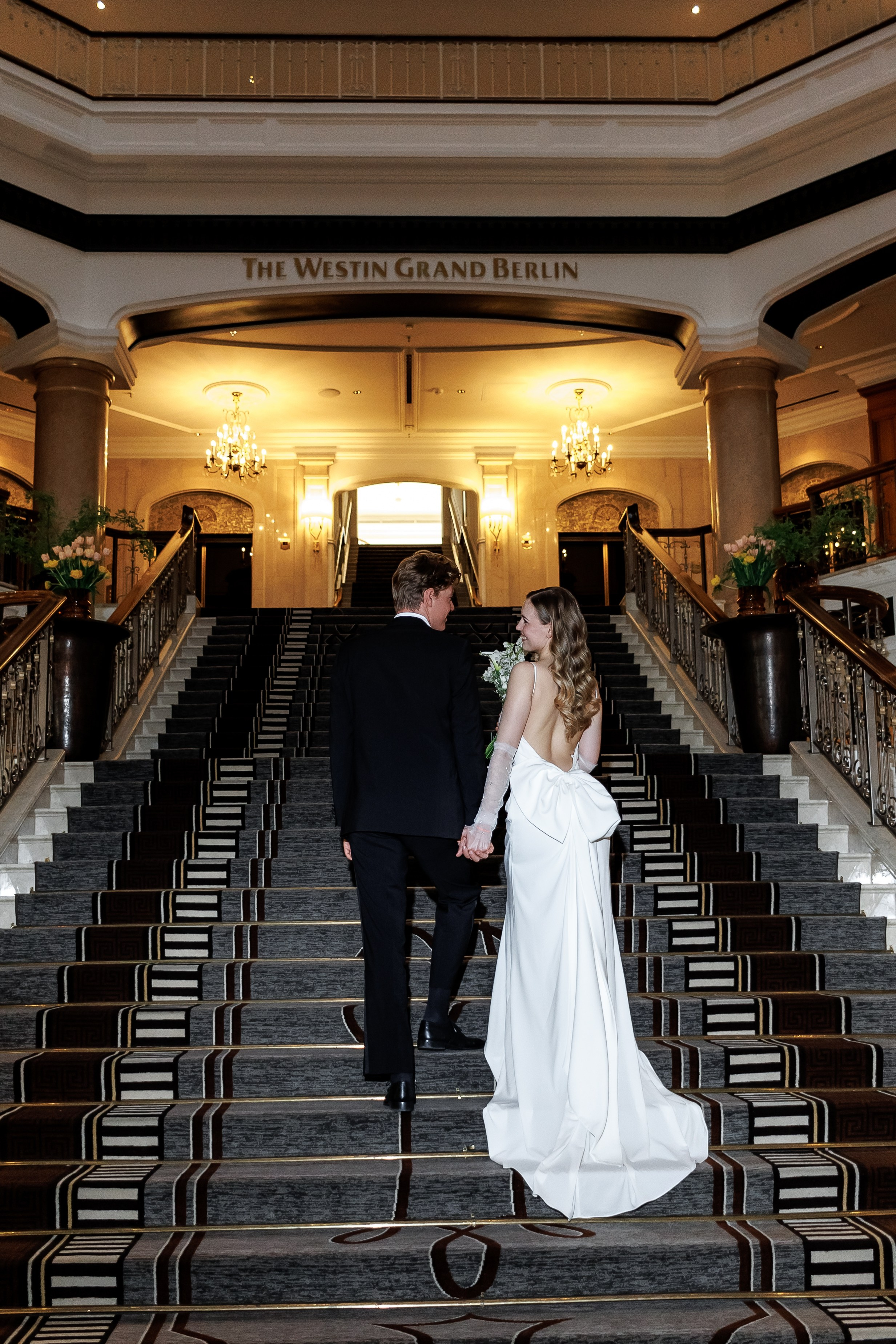 Brautpaar von hinten auf der Treppe im Westin Grand Berlin – Hochzeitsfotograf Berlin | Nataliia Schütze