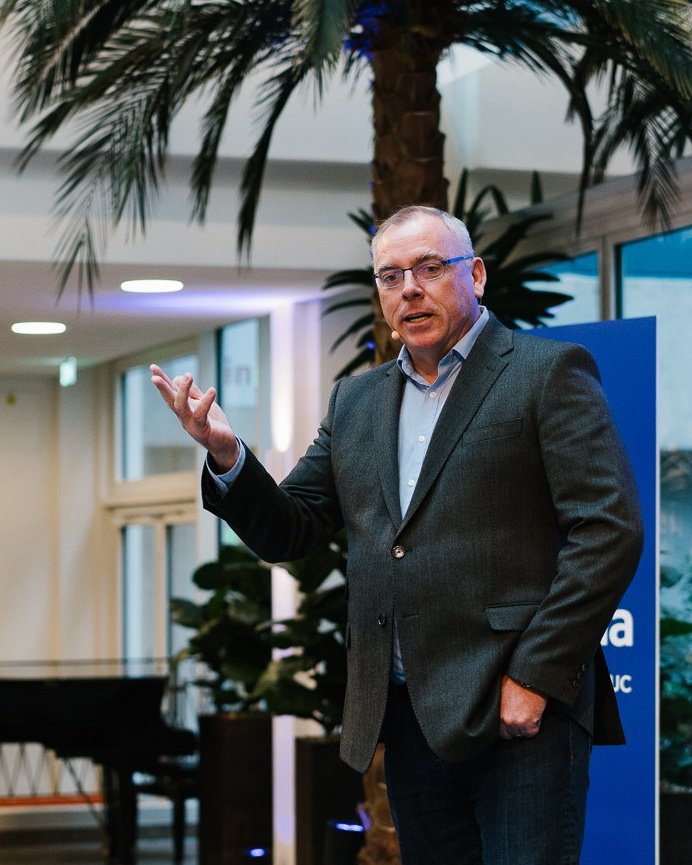 Speaker presenting on stage at a modern corporate event venue