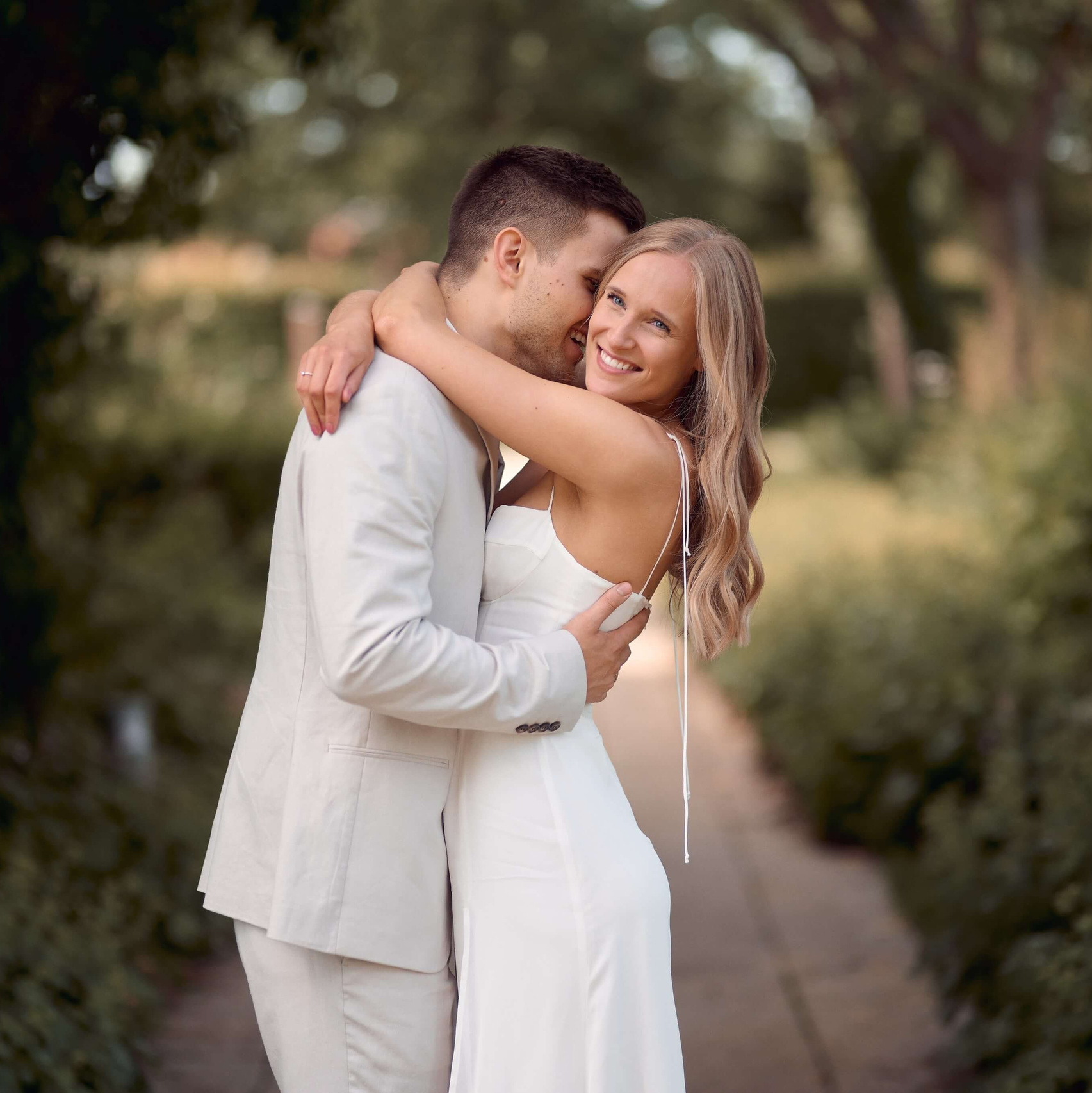 Lachendes Brautpaar umarmt sich liebevoll beim Hochzeitsshooting im Kurpark in Bad Saulgau, fotografiert von Hochzeitsfotograf Alex Fetter.