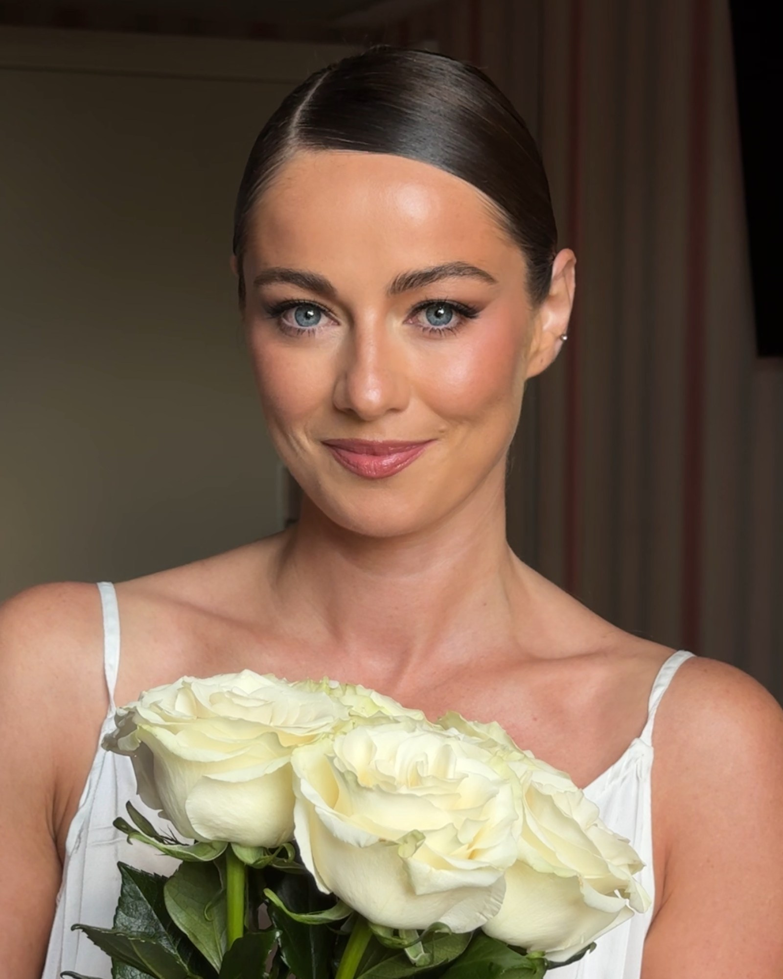 Bride with natural bridal makeup holding white roses, refined and timeless wedding beauty