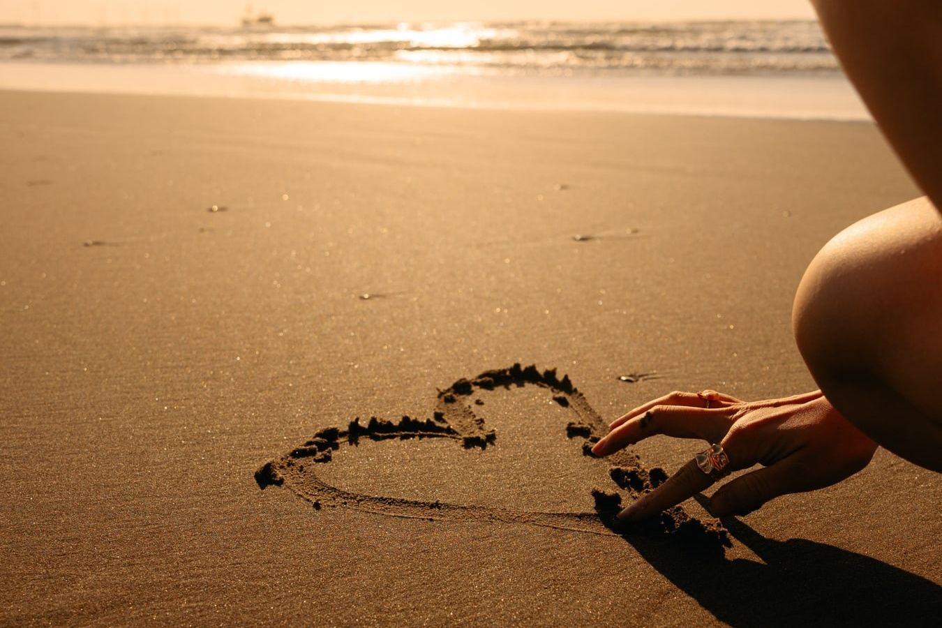 Romantic beach photoshoot in the Netherlands, heart drawn in sand at sunset