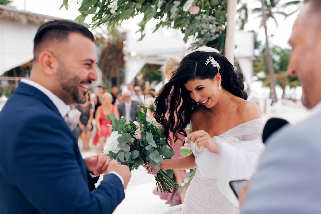 Жених и невеста смеются над шутками ведущего свадебной церемонии. 