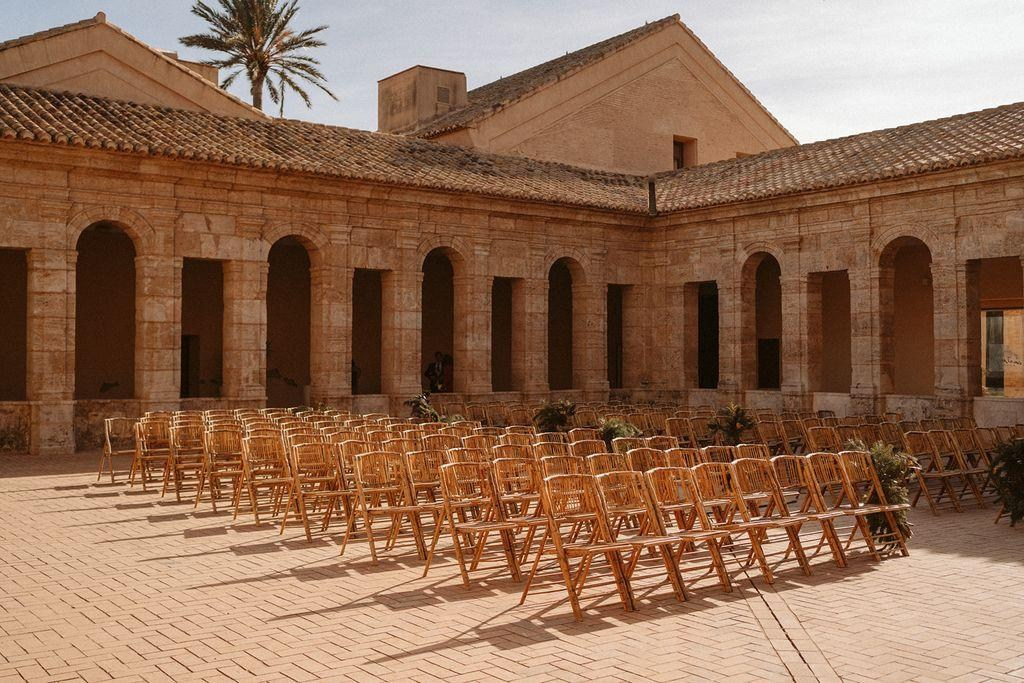 Wedding ceremony seating in the stone cloister courtyard at Cartuja de Ara Christi, framed by arched walkways.