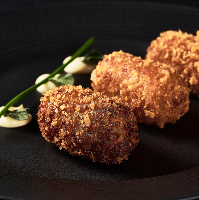 Croquetas crujientes sobre plato negro