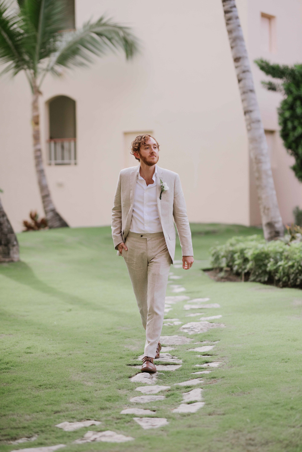 The groom poses for a photographer at a wedding photo shoot. 