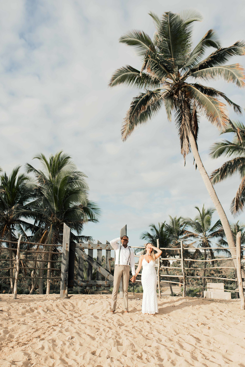 The bride and groom pose for a picture with their hands over their eyes. 