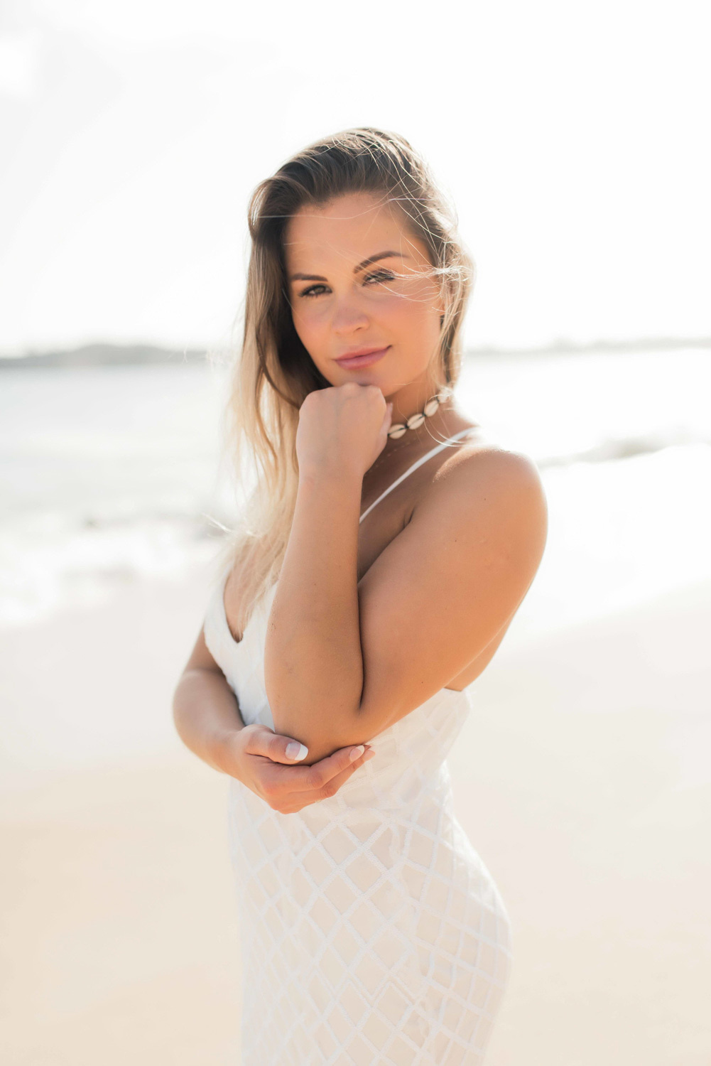 The bride looks into the camera to the photographer, holding her chin with her hand. 