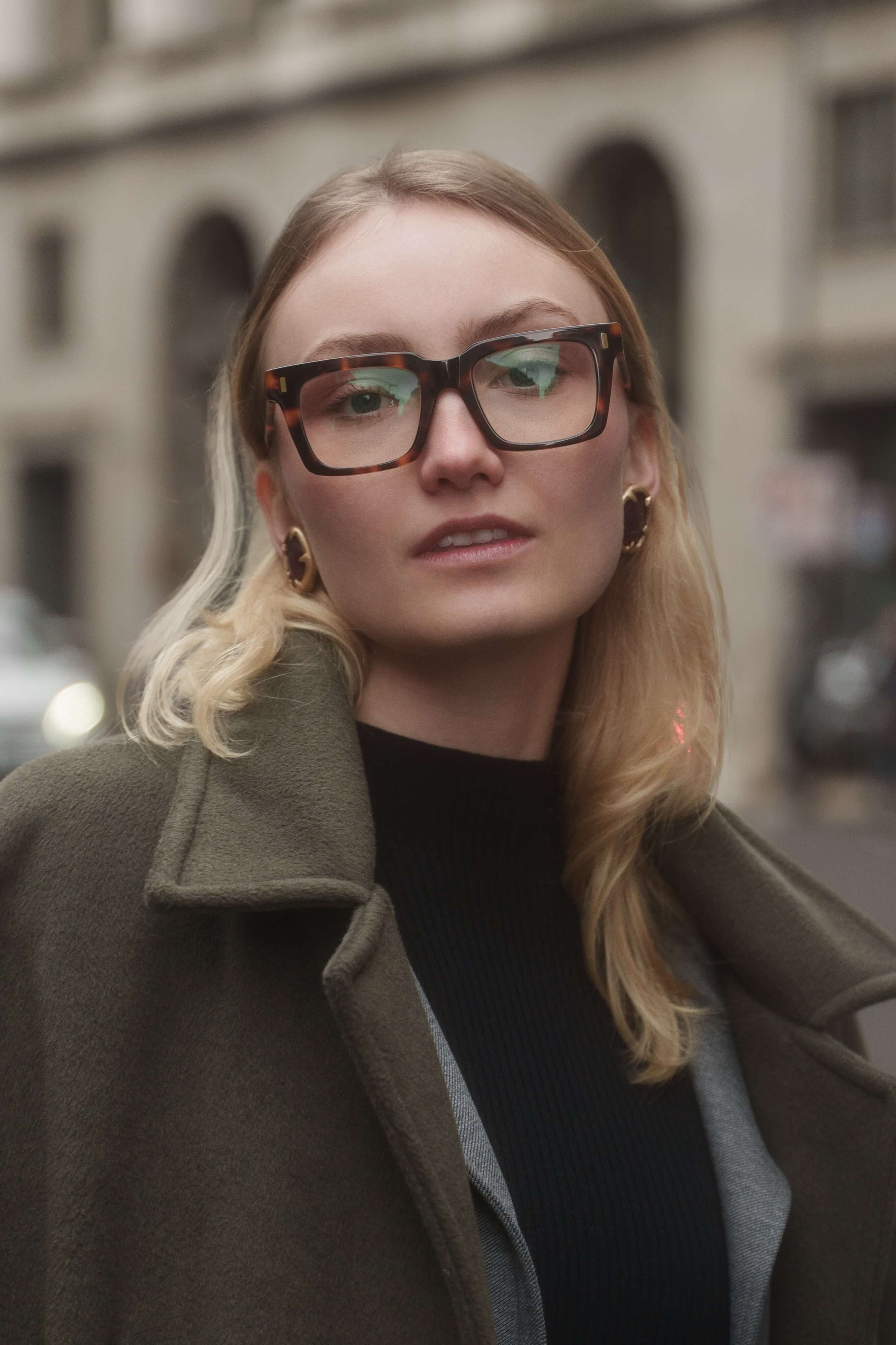 Close-up portrait of female model wearing thick tortoiseshell eyewear, captured on location in Milan