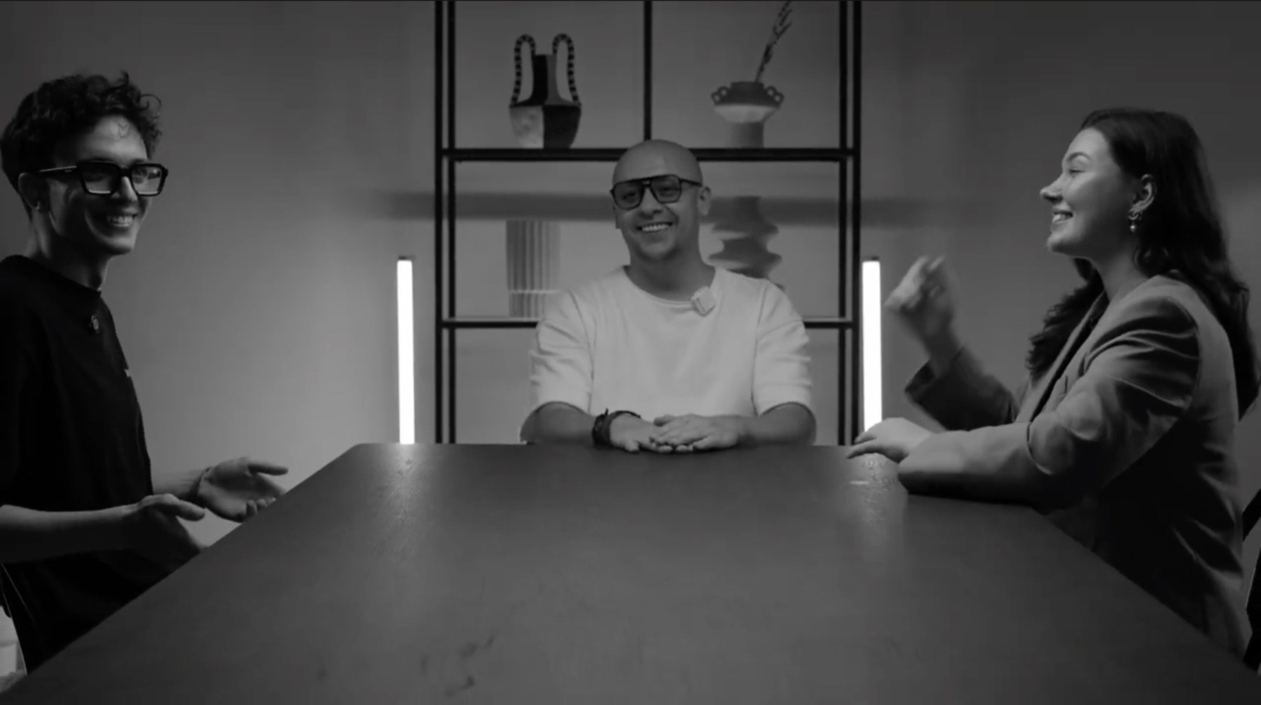 Wide black-and-white view of three speakers during a multi-camera podcast production in the UAE