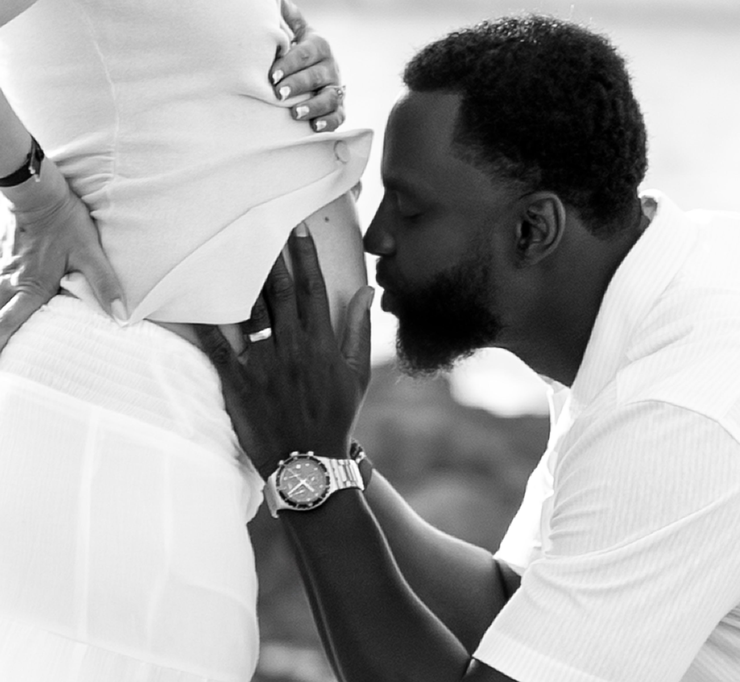 Emotional maternity and family photoshoot in Valencia, Spain, capturing a close-up moment of parents and child sharing affection around the pregnant mother, photographed in black and white to emphasize love, connection, and anticipation of a new baby.