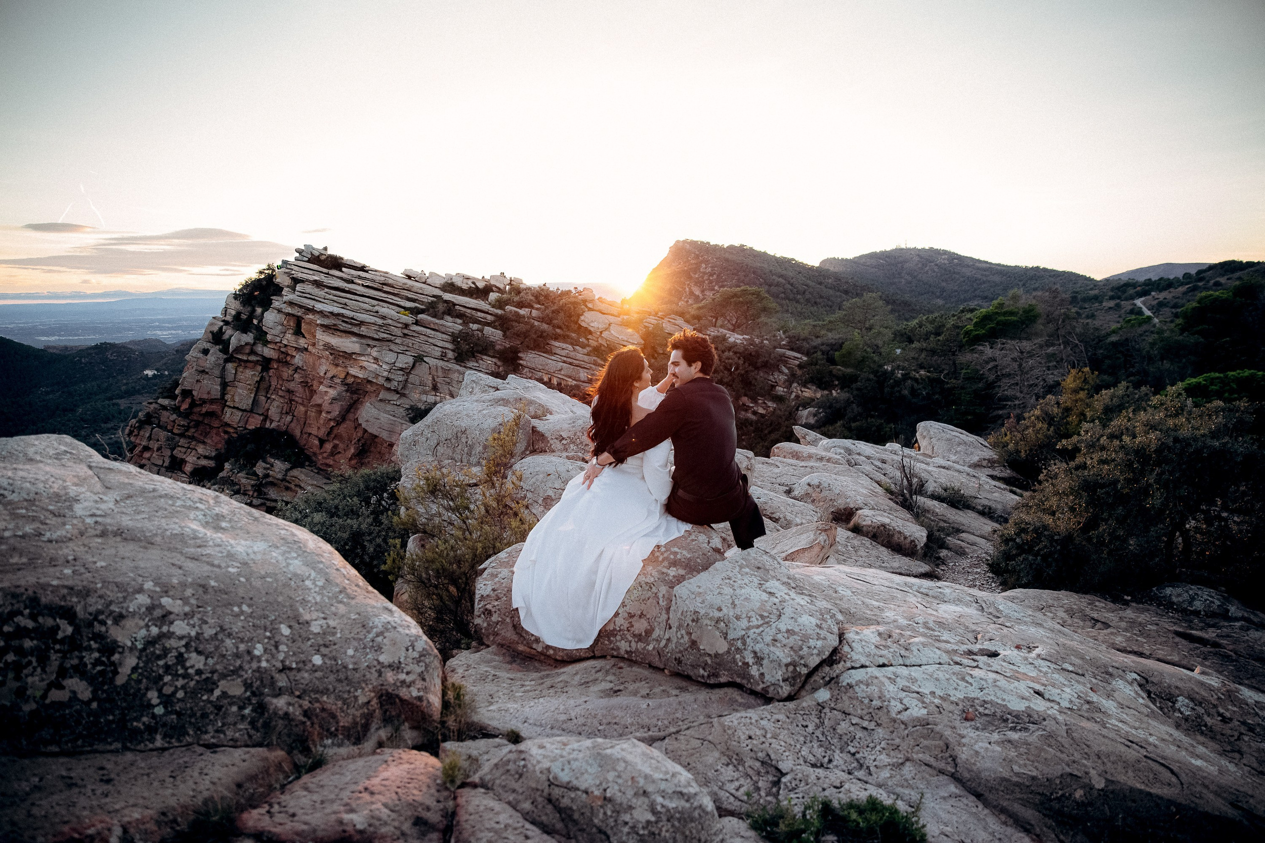 sunset wedding portraits in Valencia, Spain with couple embracing on rocky landscape in golden light