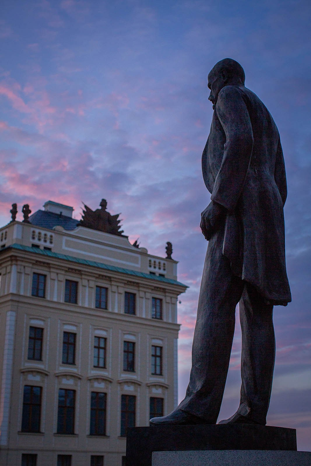 The statue of T. G. Masaryk overlooking Prague Castle at sunrise, with the city skyline in the distance
