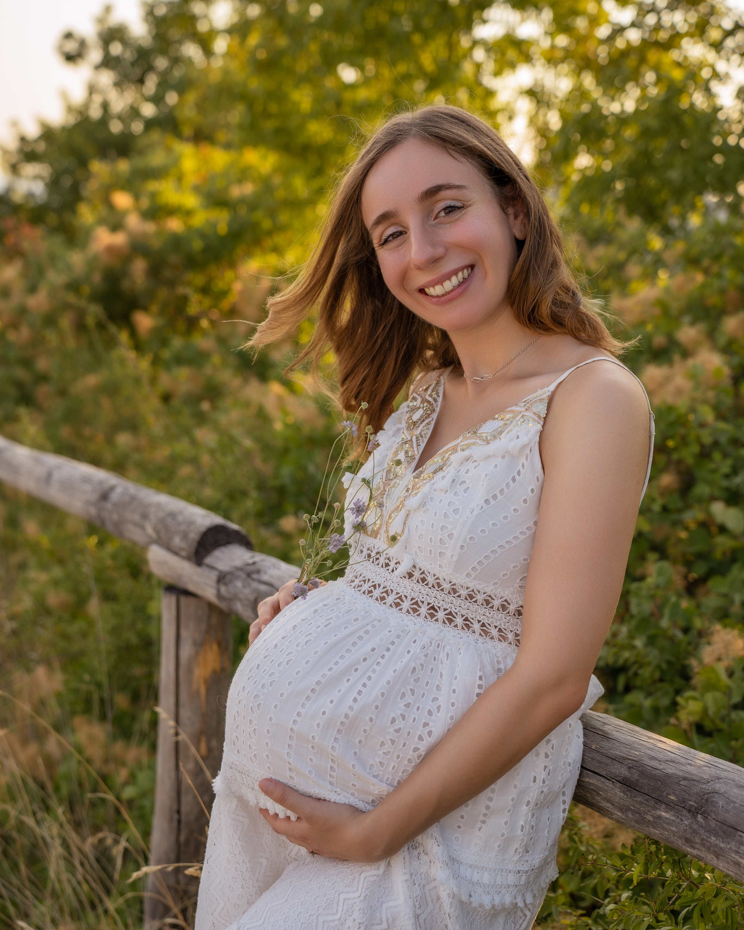 Futura mamma in abito bianco durante un servizio fotografico gravidanza all'aperto tra il verde dei Colli Euganei.
