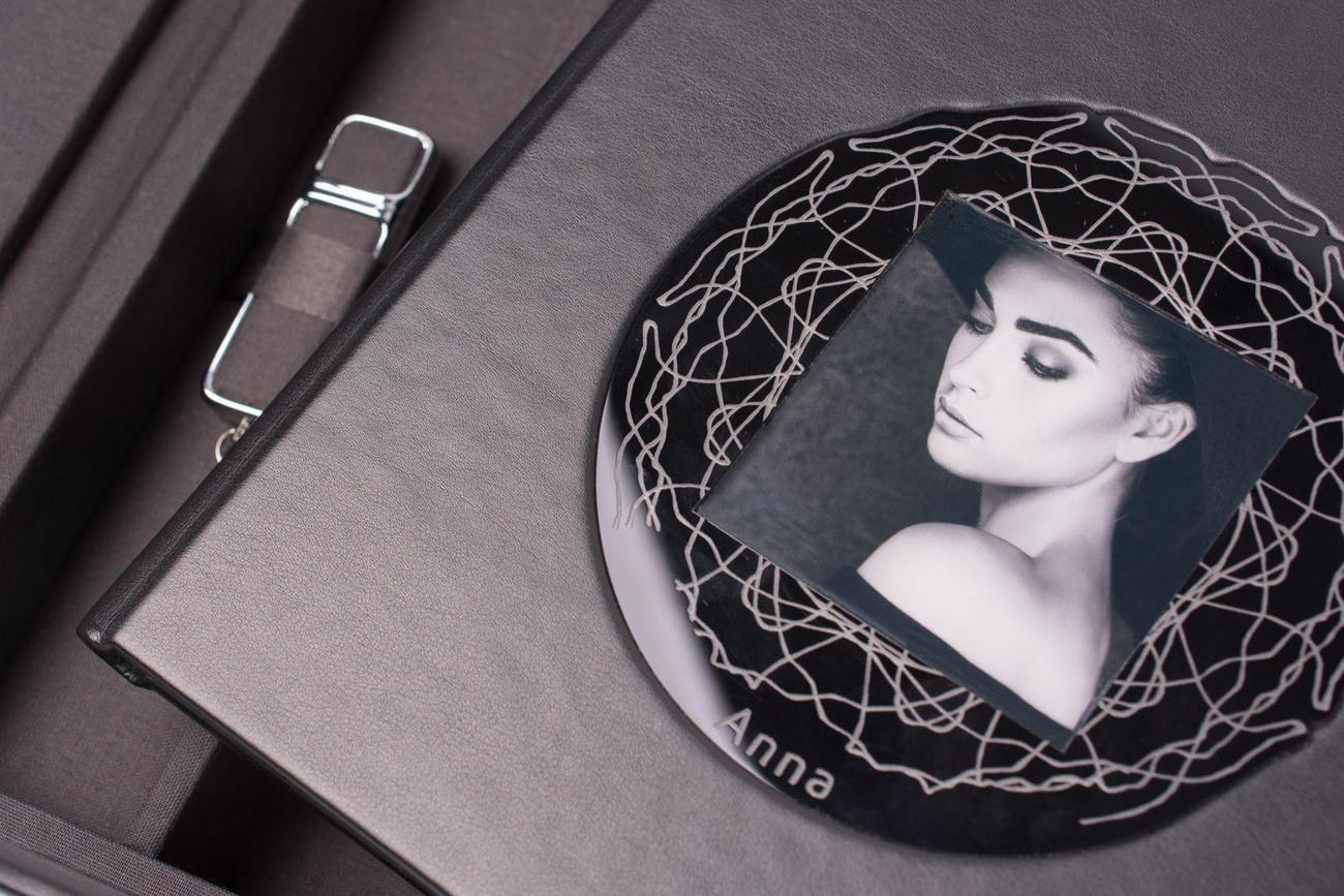 Album fotografico personalizzato con copertina in tessuto grigio e una finestra circolare che rivela un ritratto in bianco e nero, rifinito con il nome inciso, pronto a conservare i momenti più belli di un matrimonio.